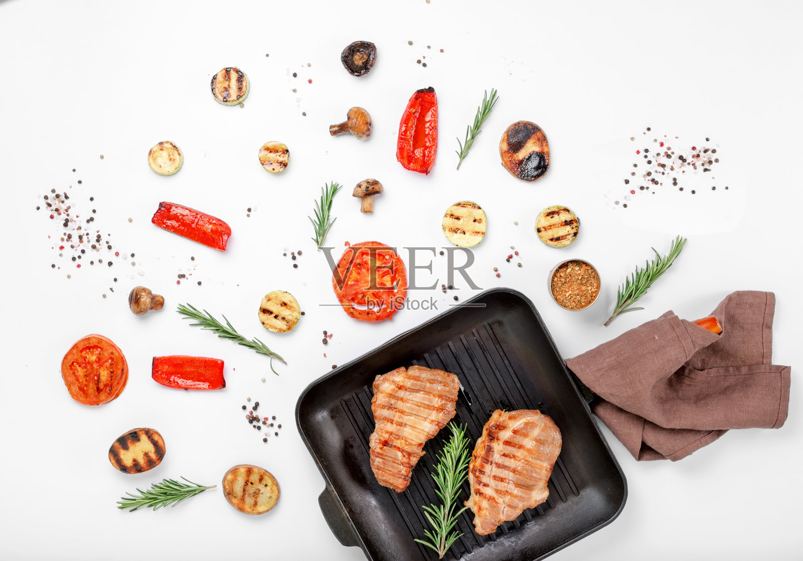 铸铁烤锅与牛排烤架在白色的背景与烤蔬菜照片摄影图片