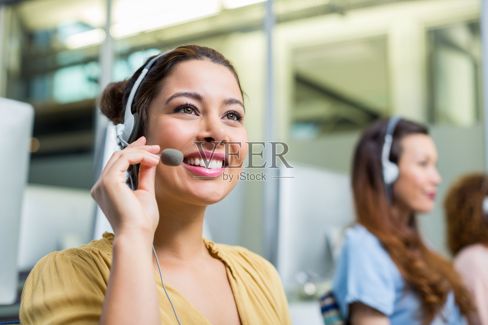 面带微笑的女客户服务主管在桌前用耳机说话照片摄影图片