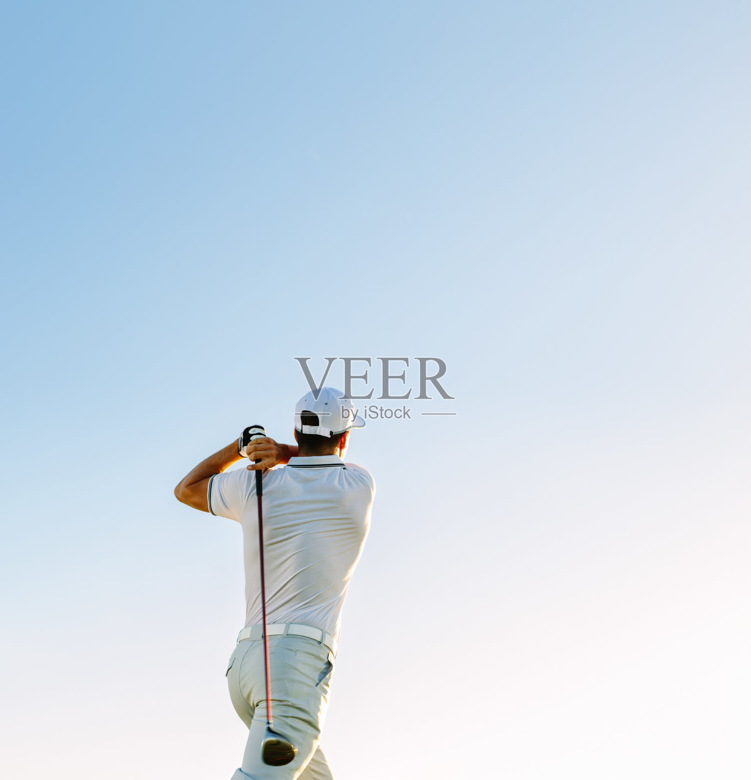 晴朗的天空下挥舞着高尔夫球杆的男子照片摄影图片