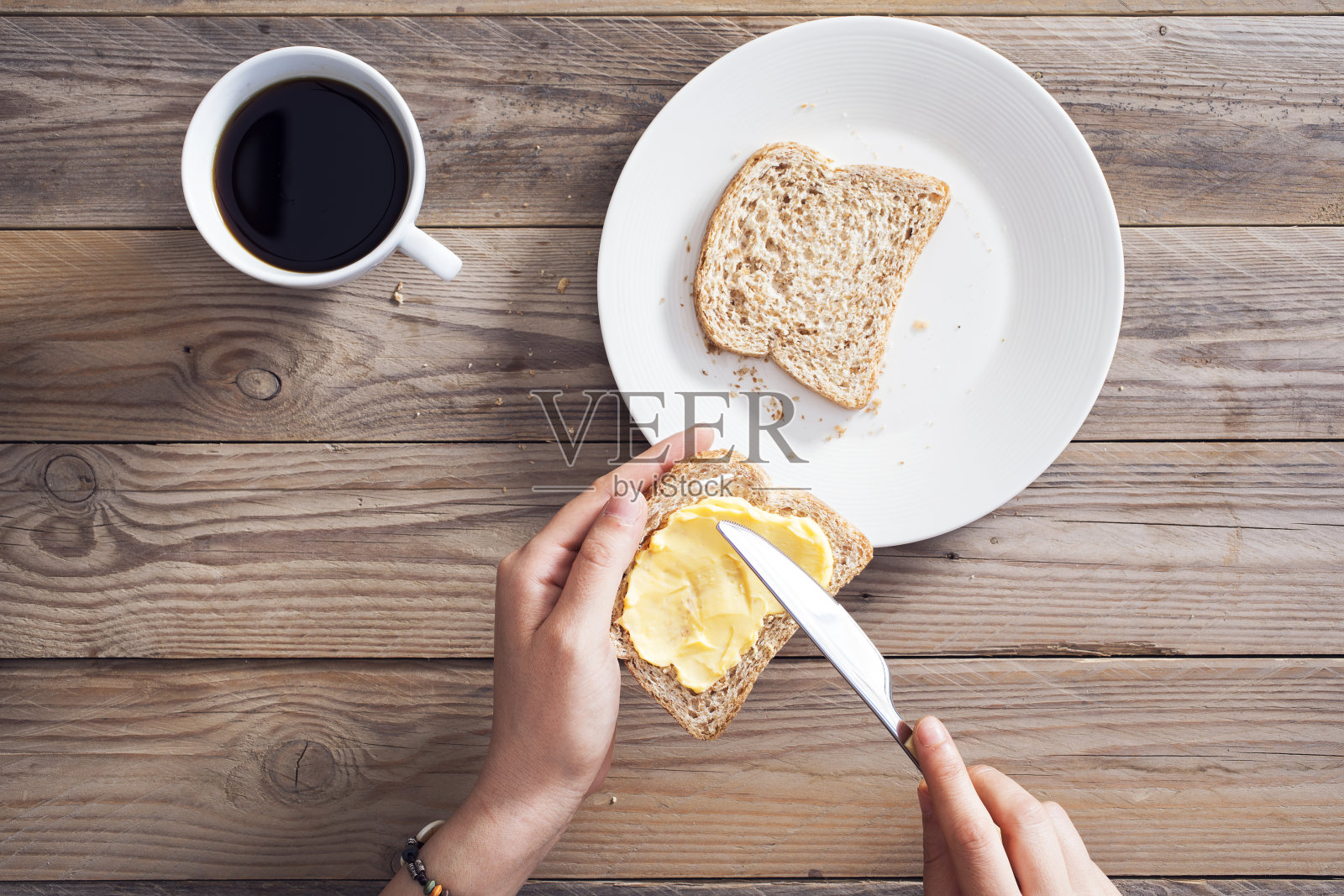 女人用手把黄油涂在切片面包上照片摄影图片