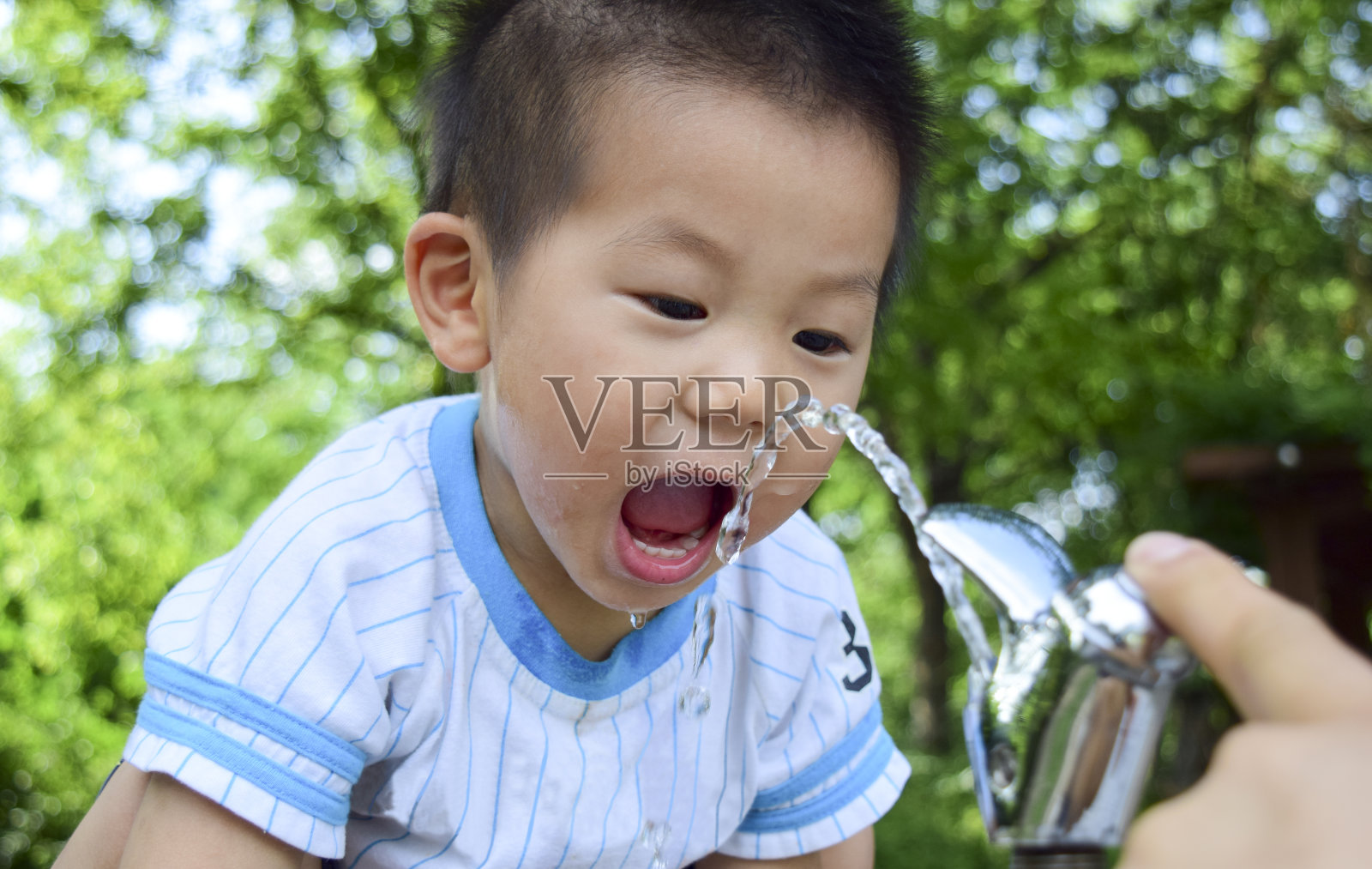 一个孩子在公园里吃自来水照片摄影图片