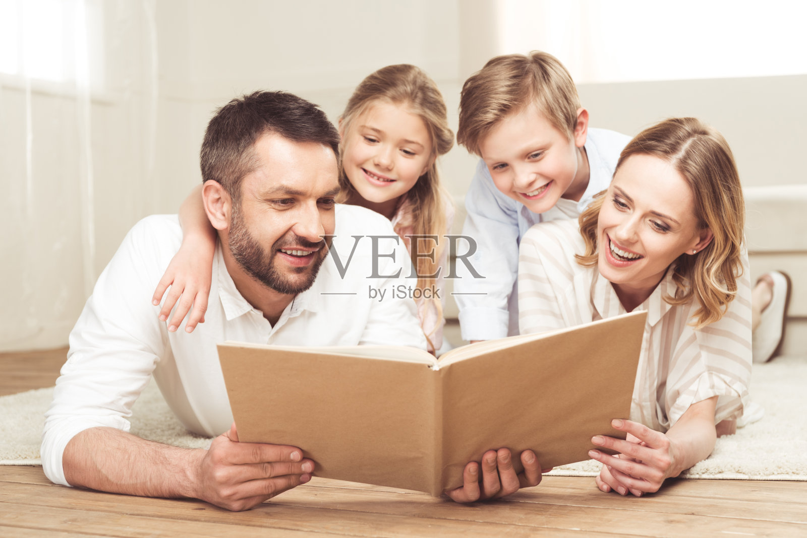 一家人微笑着一起躺在家里的地板上看书照片摄影图片