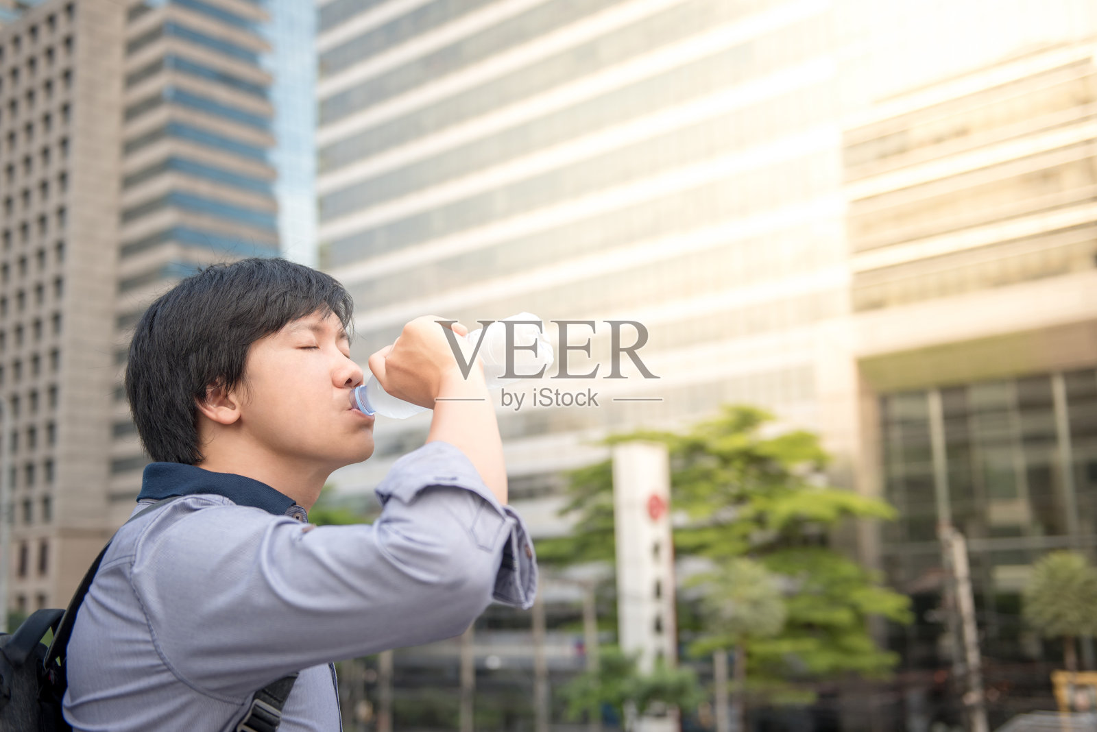 年轻的亚洲人在城市里喝一瓶水照片摄影图片