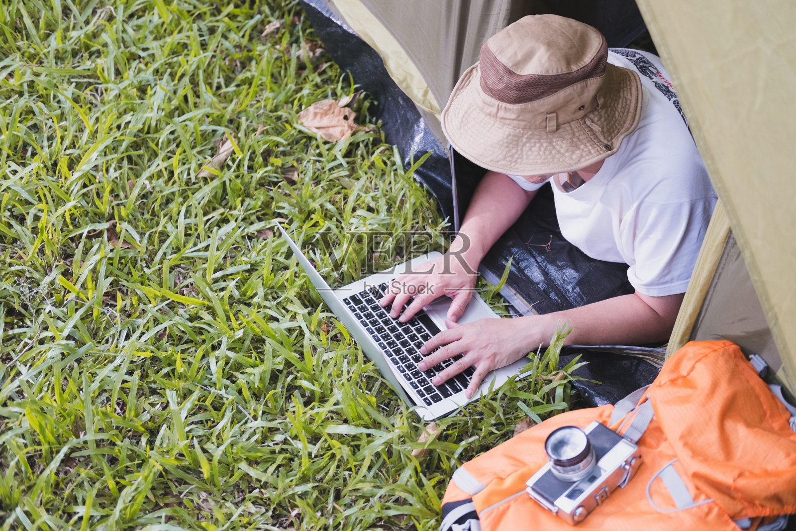 一名年轻游客躺在森林露营地的帐篷里使用笔记本电脑。夏天的户外活动。在国家公园探险旅行。照片摄影图片