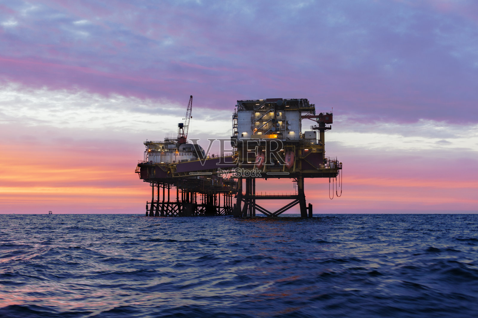 日落时海上石油平台的剪影照片摄影图片