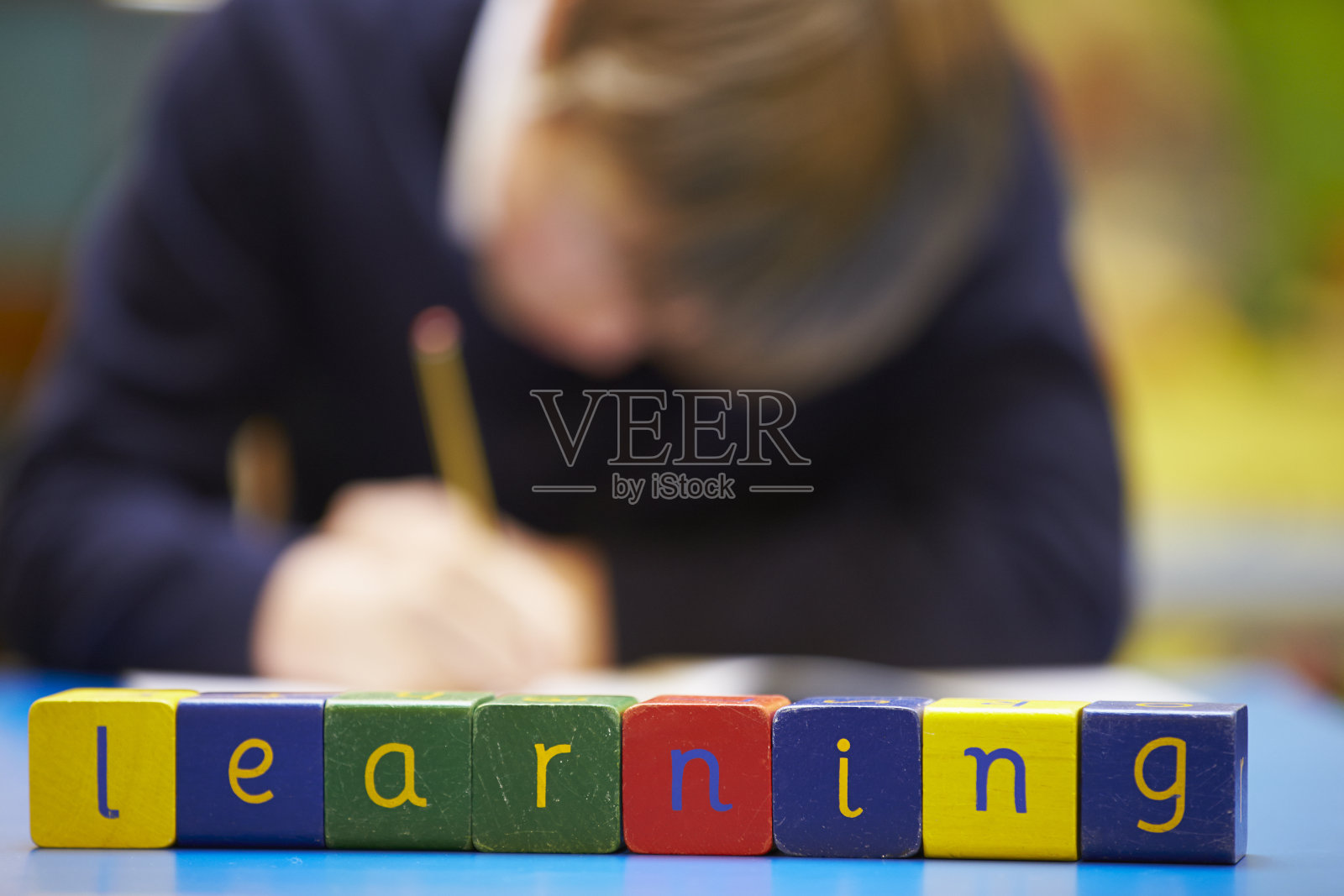 单词“Learning”在小学生后面的木块中拼写照片摄影图片
