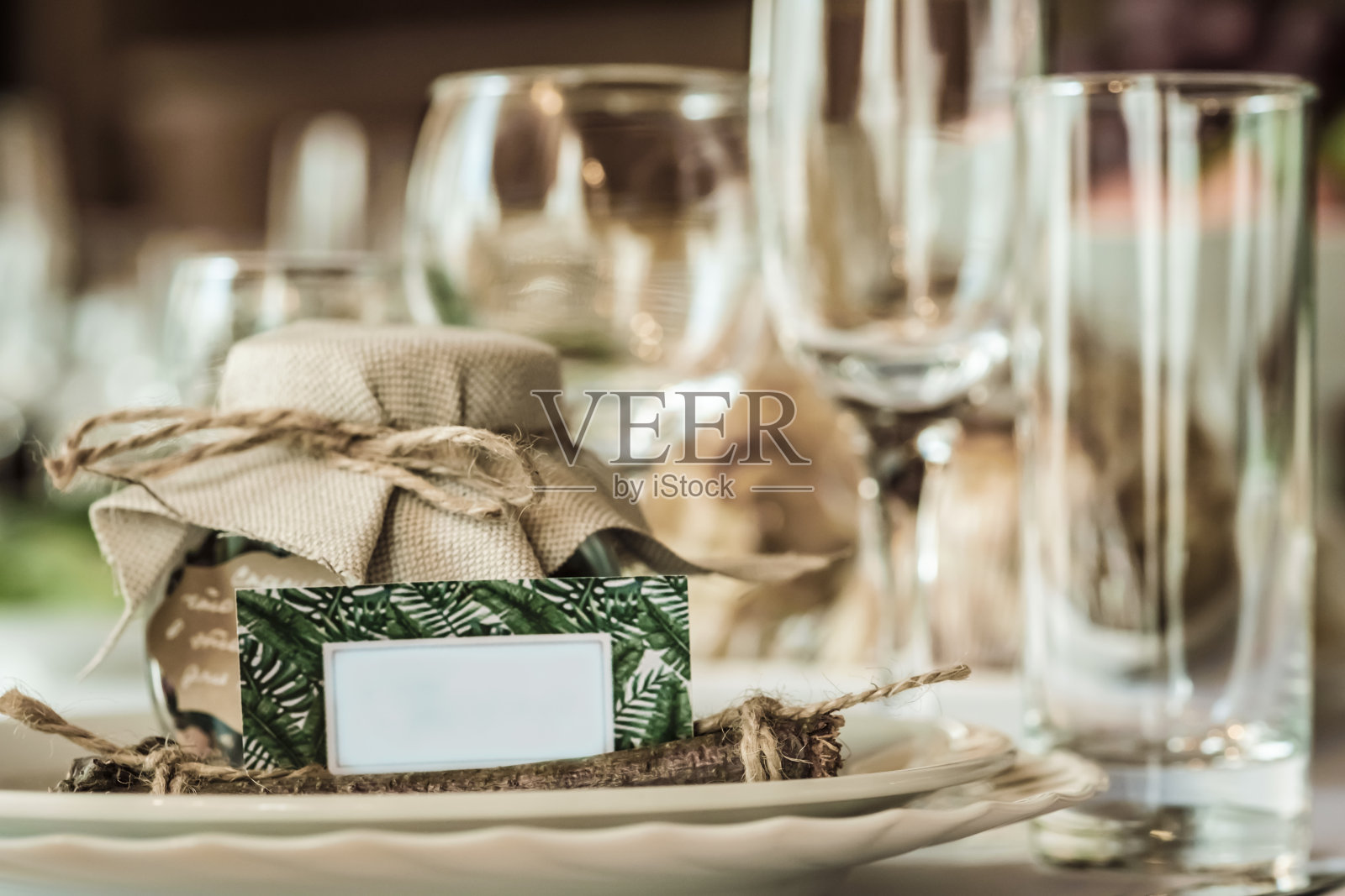 在漂亮舒适的餐厅里为婚礼庆典设置的质朴的餐桌。酒杯，盘子和桌上的食物。客人们在一个质朴的罐子里互相补充。带有文本空间的漂亮卡片照片摄影图片