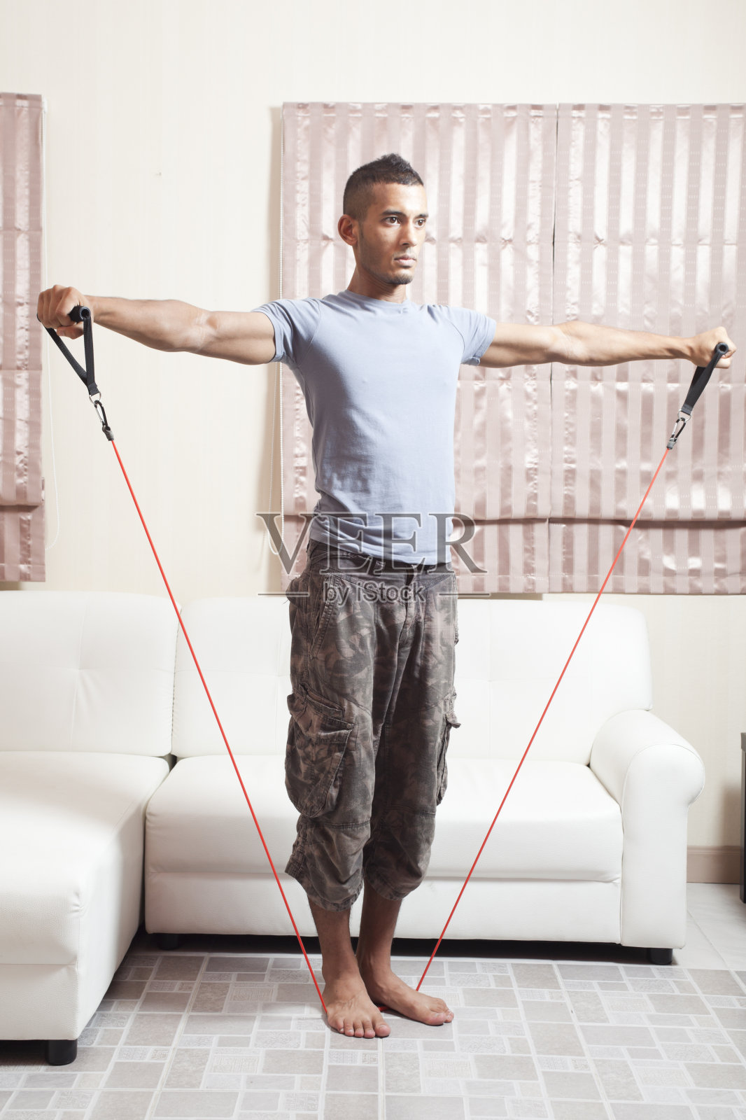 肌肉发达的男性在家里使用阻力带。侧举照片摄影图片
