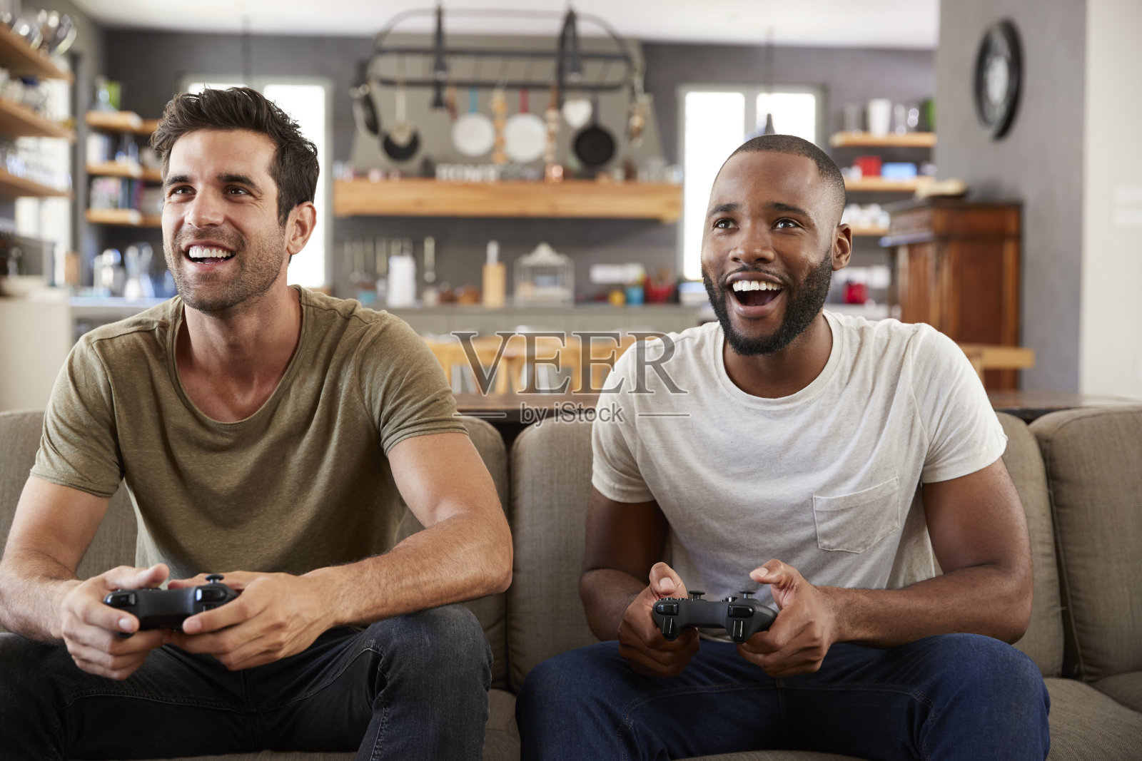 两个男性朋友坐在客厅的沙发上玩电子游戏照片摄影图片