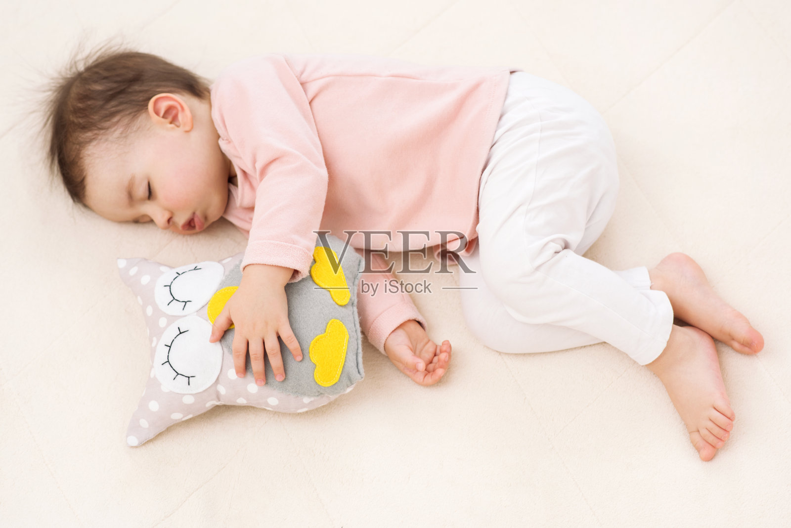 睡觉和做梦漂亮的小女孩在床上有一个猫头鹰玩具照片摄影图片