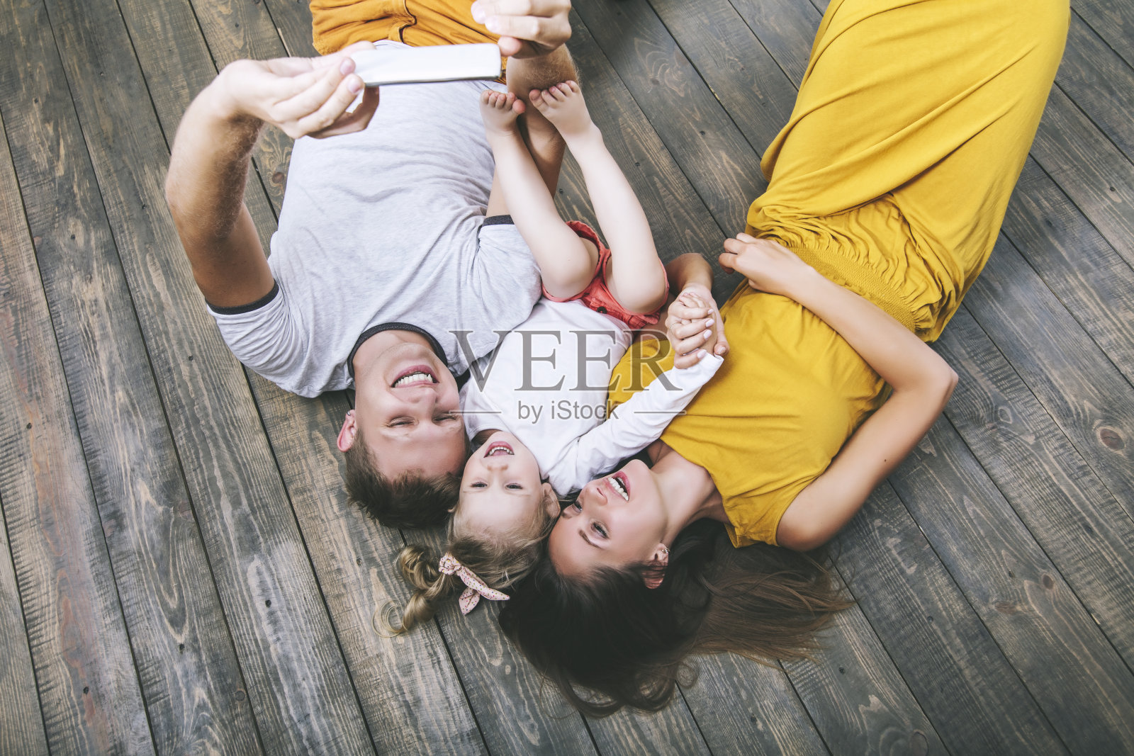 幸福美丽的年轻家庭爸爸，妈妈和女儿在家里用手机自拍微笑照片摄影图片