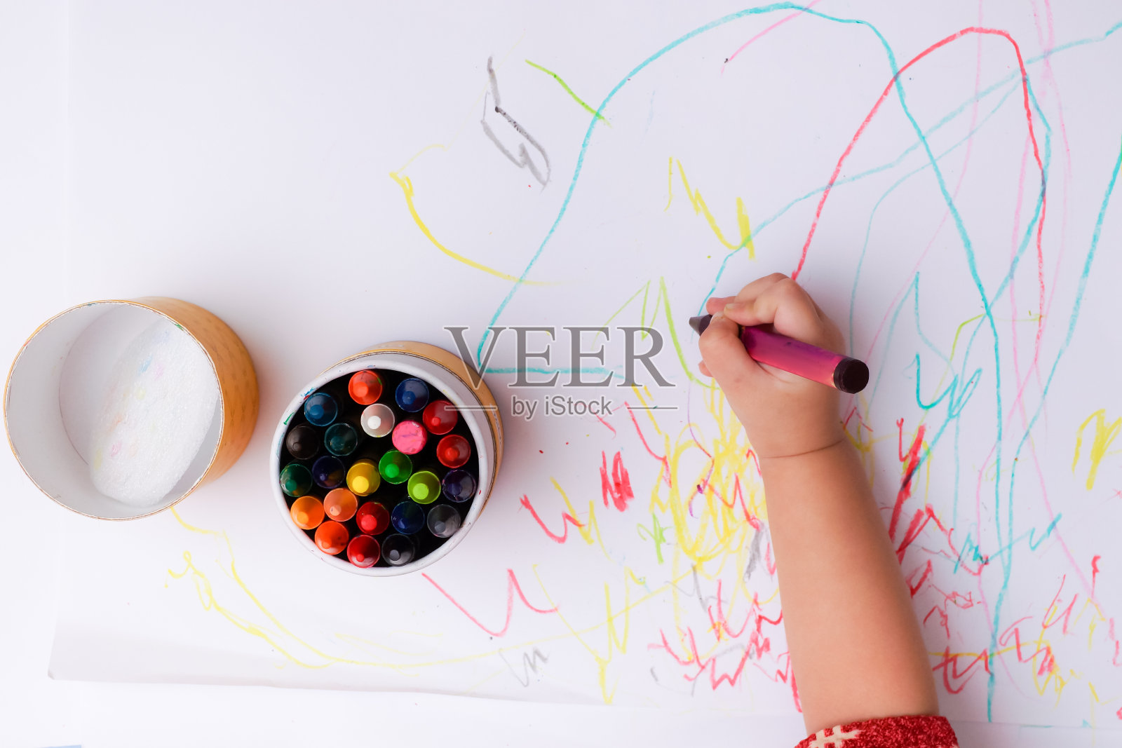 一只婴儿用彩色蜡笔画线条和形状的手。照片摄影图片