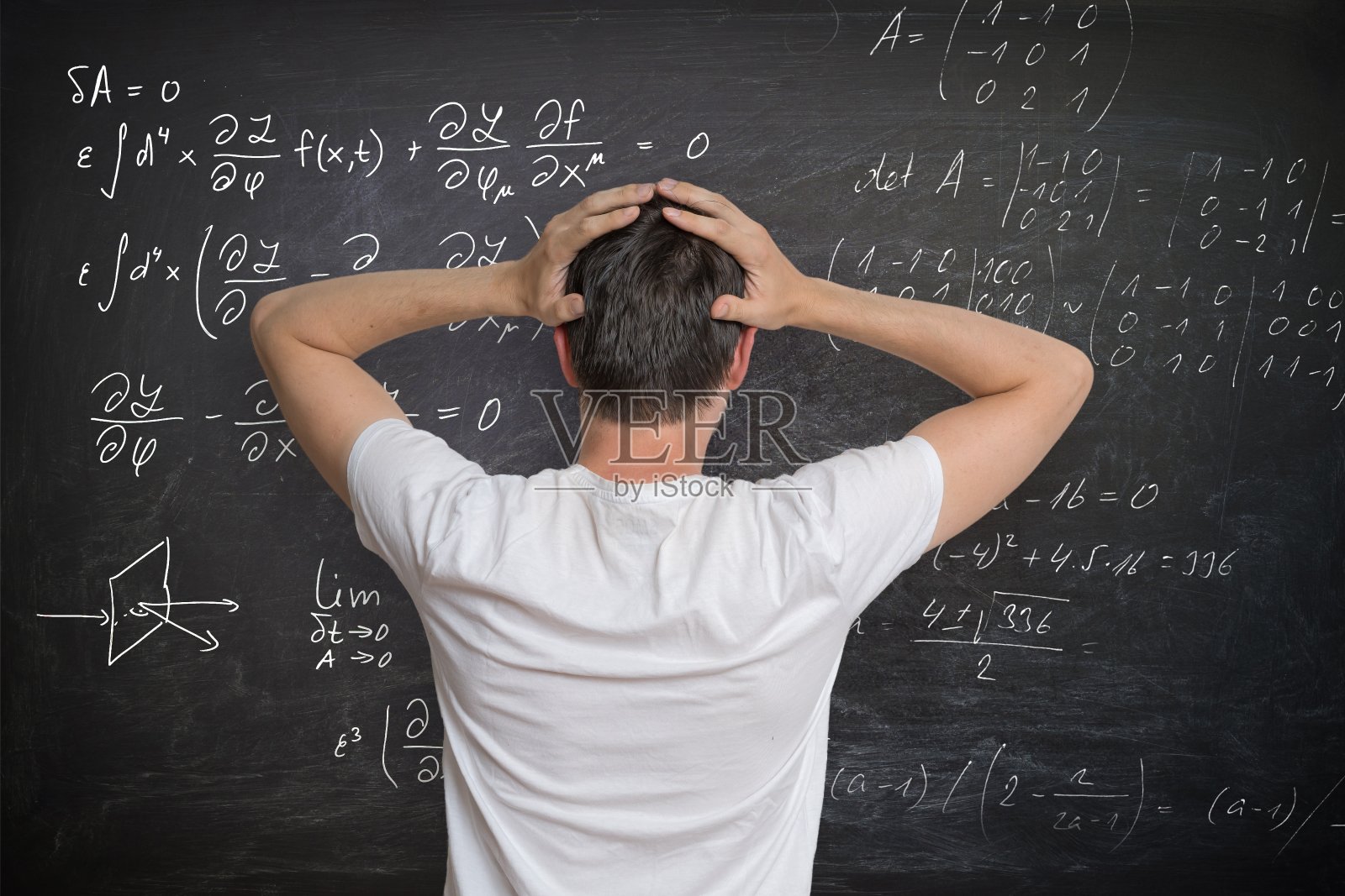 一个年轻人正在黑板上解数学题，他很困惑。照片摄影图片