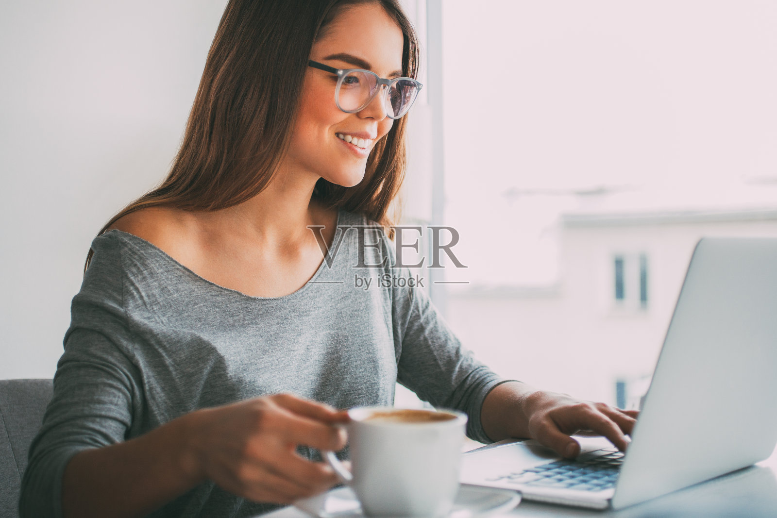 在笔记本电脑前喝咖啡的快乐女商人照片摄影图片