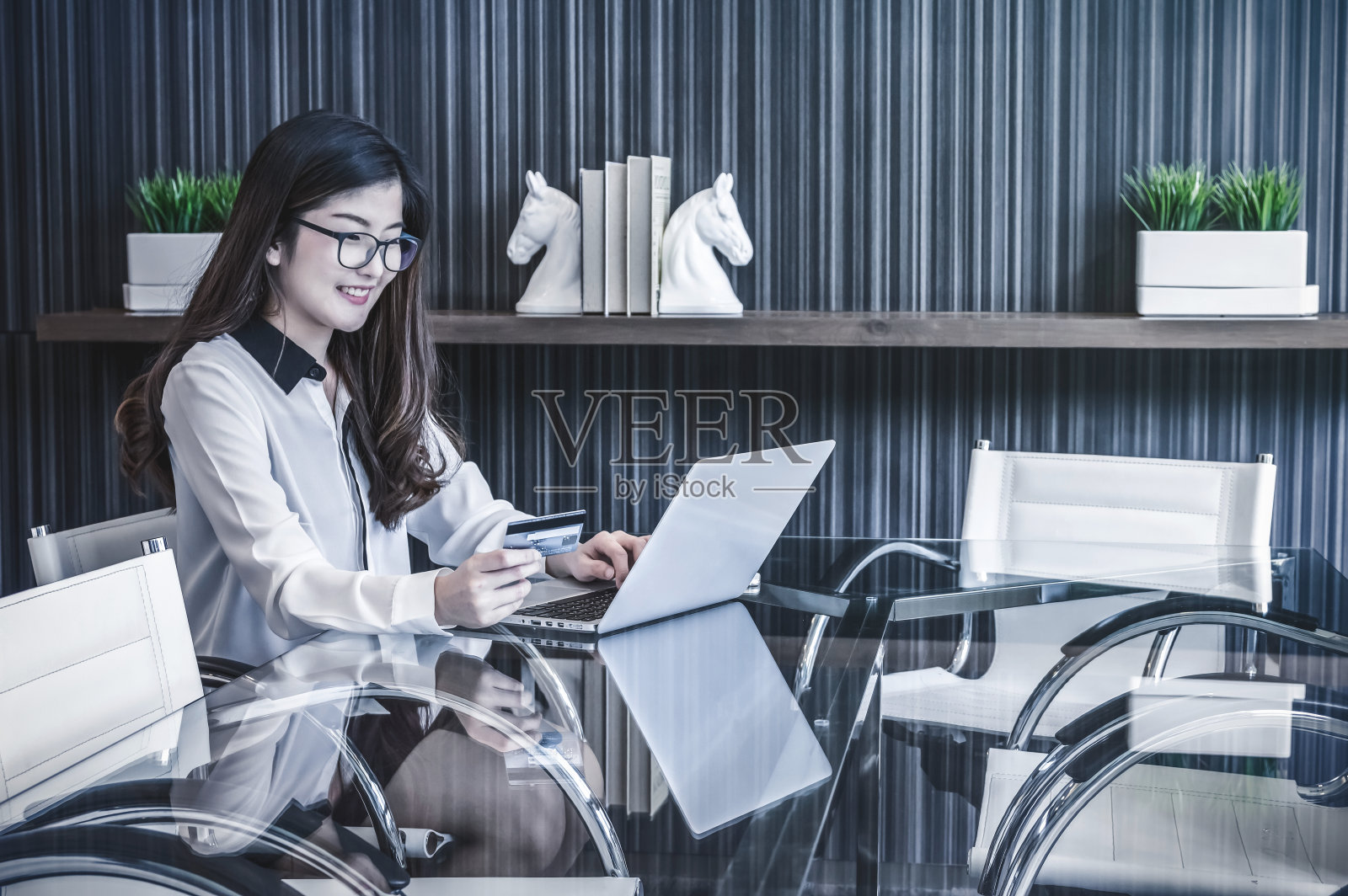 微笑的亚洲美丽的年轻女商人坐在工作场所使用笔记本电脑通过信用卡网上购物，商业生活方式和技术概念照片摄影图片