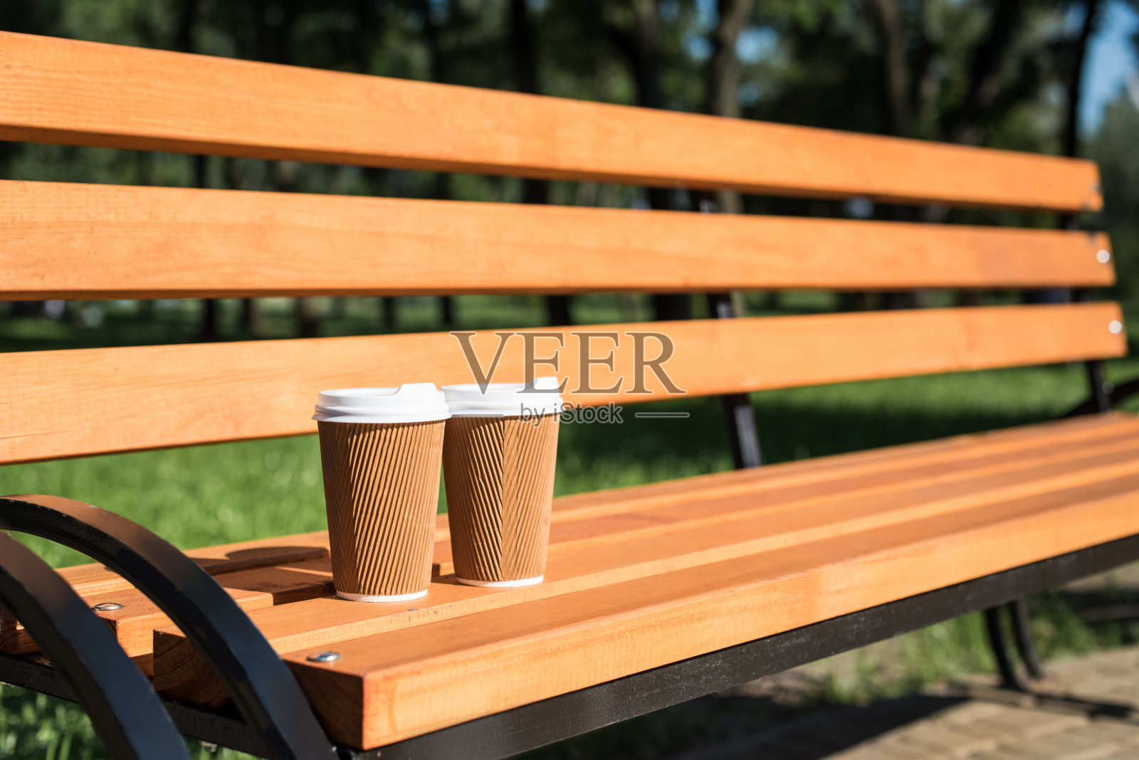 公园木凳上的两个一次性咖啡杯的特写照片摄影图片