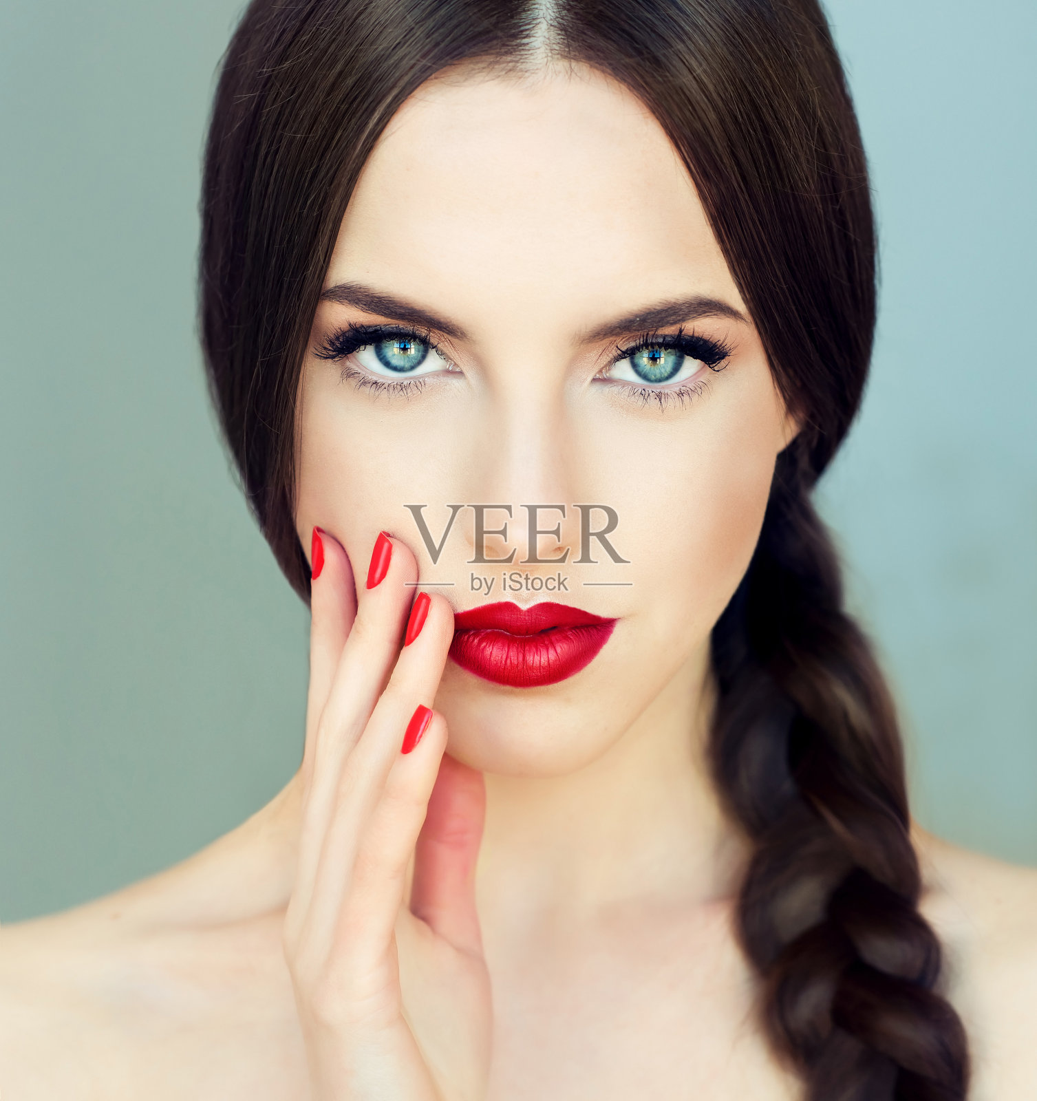 年轻的黑发女模特，梳着长长的辫子，修着红色的指甲。照片摄影图片