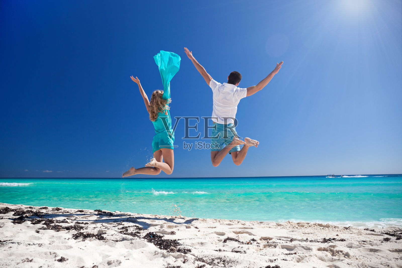 快乐的情侣在海滩上跳照片摄影图片