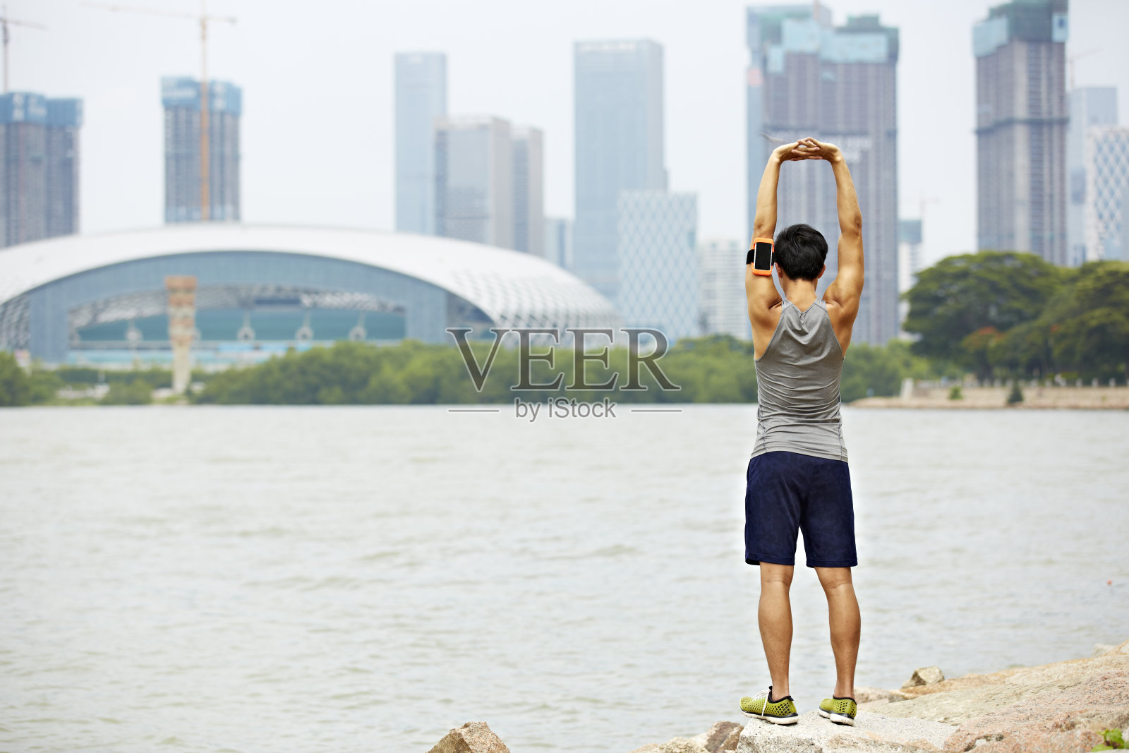 年轻的亚洲慢跑者在公园里伸展手臂照片摄影图片