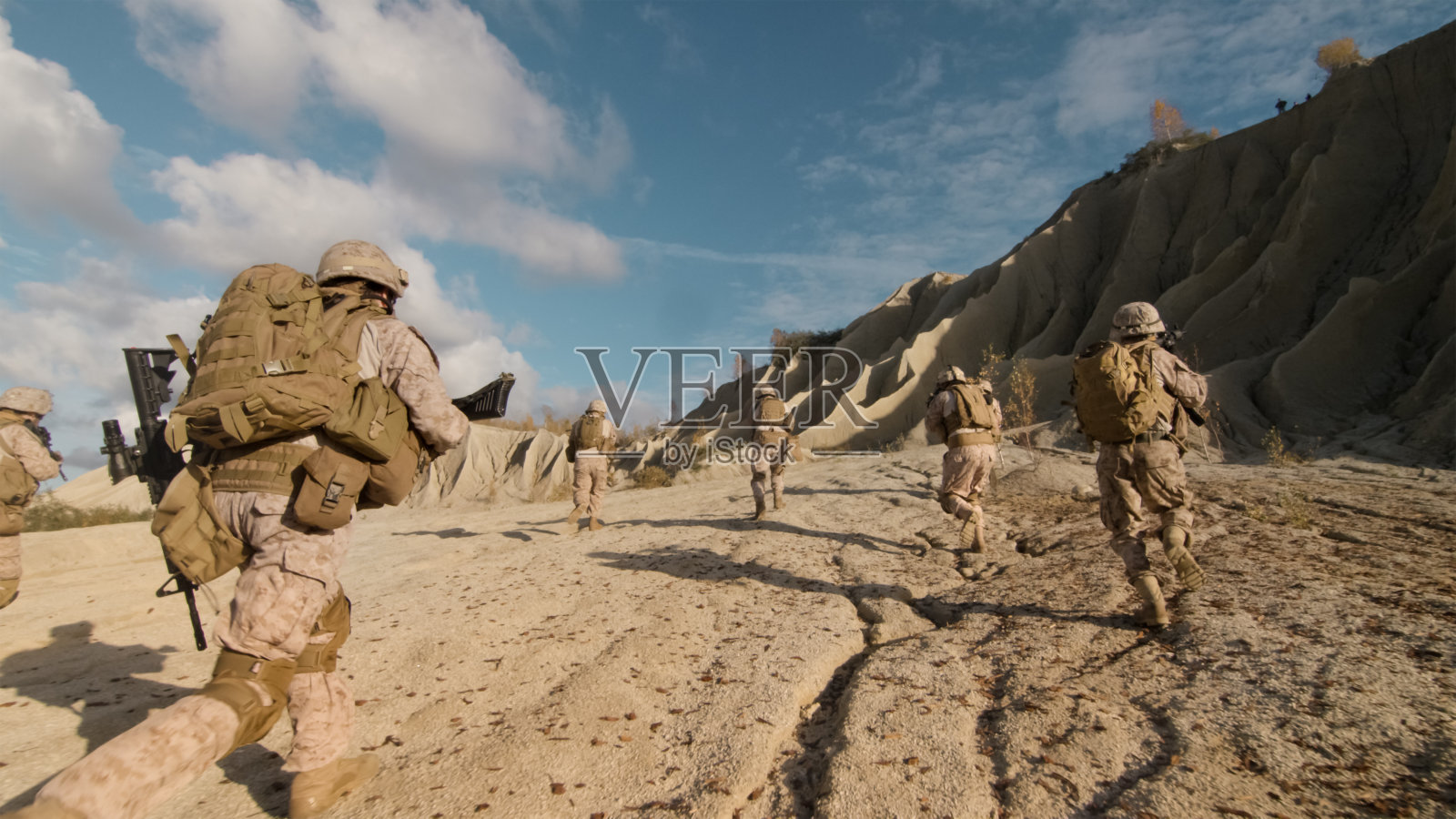 在沙漠中进行军事行动时，一队士兵向前跑并攻击敌人。照片摄影图片