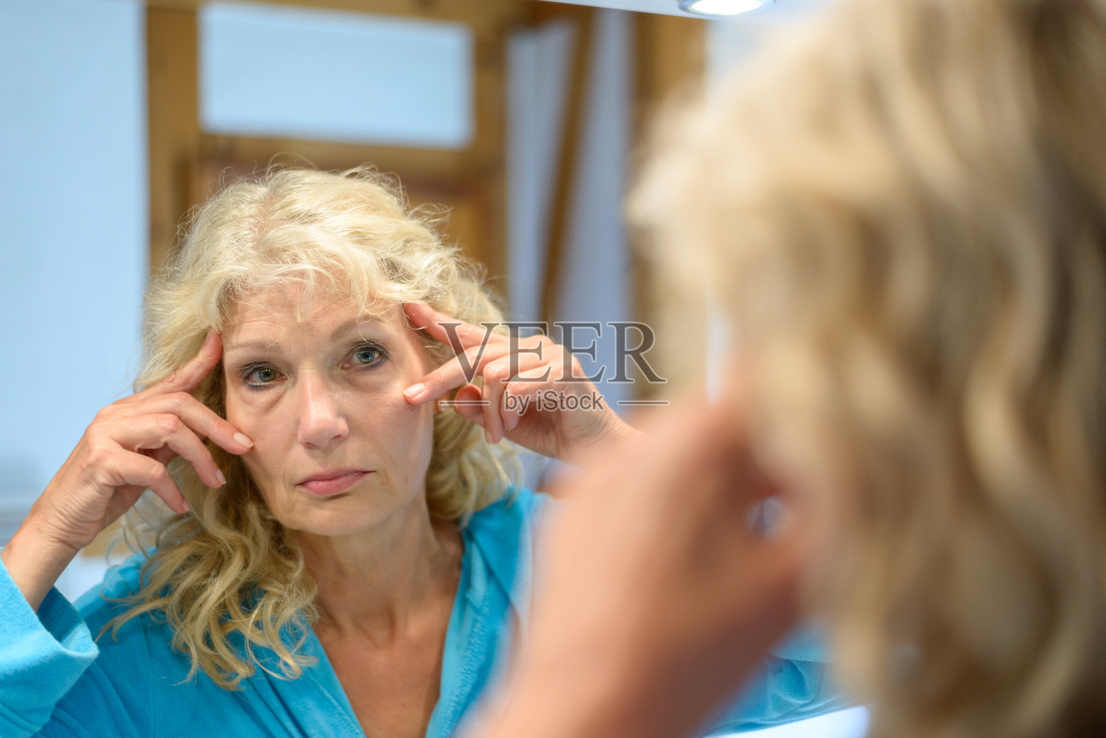 一位年长的女士在镜子前检查自己的皱纹照片摄影图片