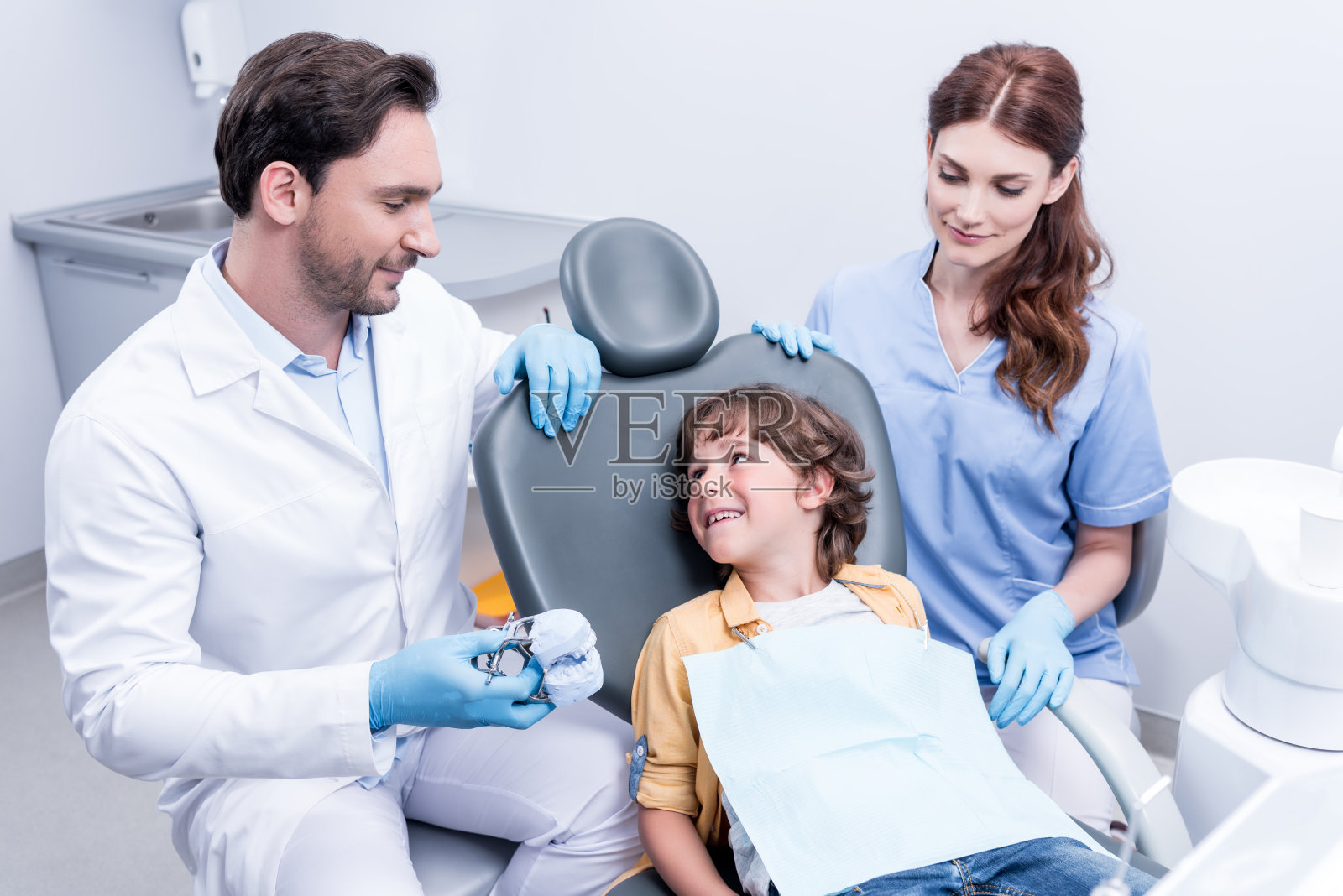 牙医在牙科诊所为小男孩检查牙齿做准备照片摄影图片