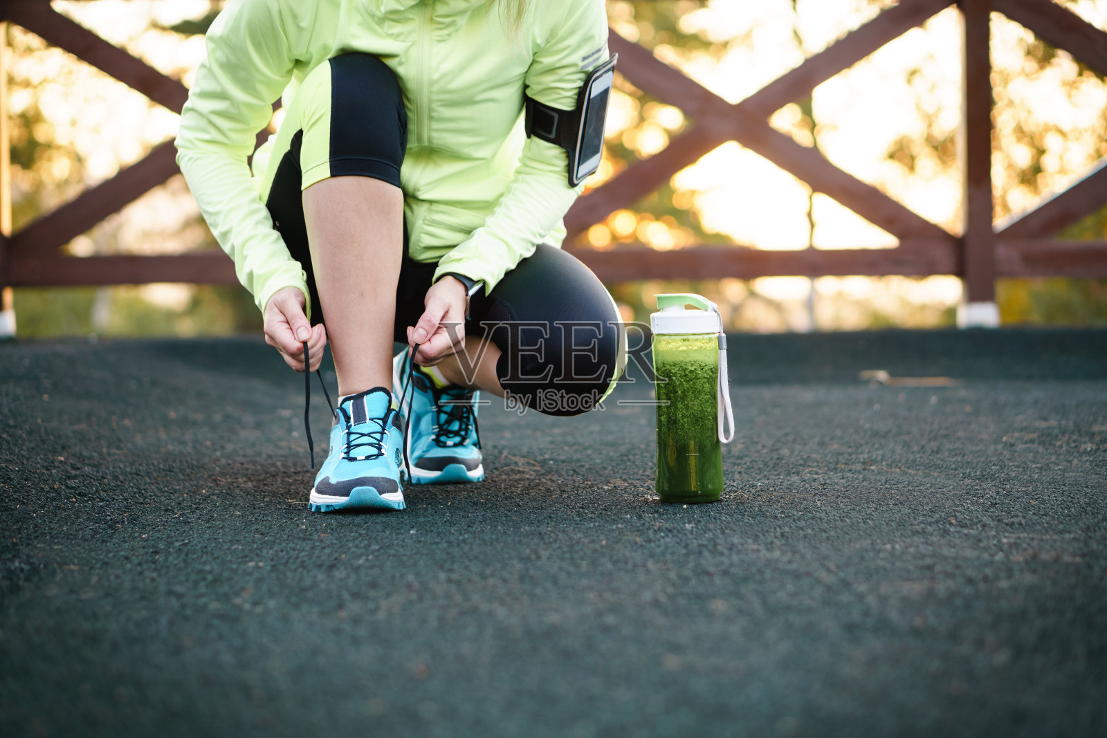 绿色排毒奶昔杯和女人的鞋带跑步前锻炼。照片摄影图片