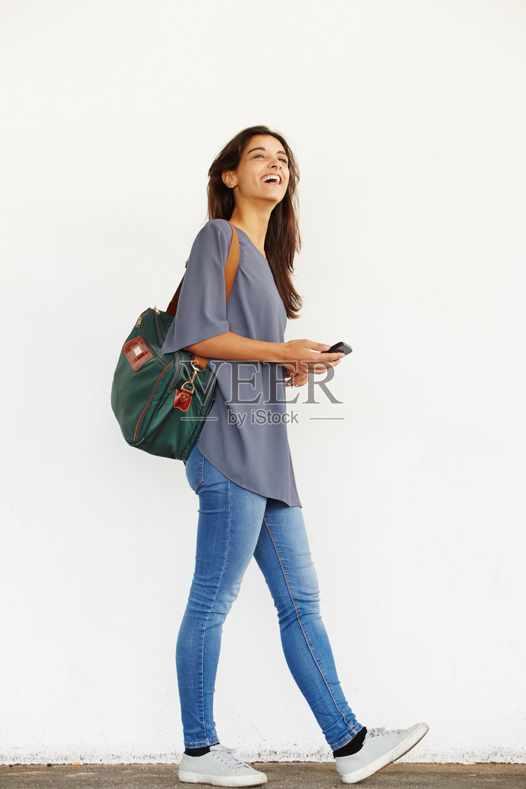 快乐的年轻女人拿着手机在外面散步照片摄影图片