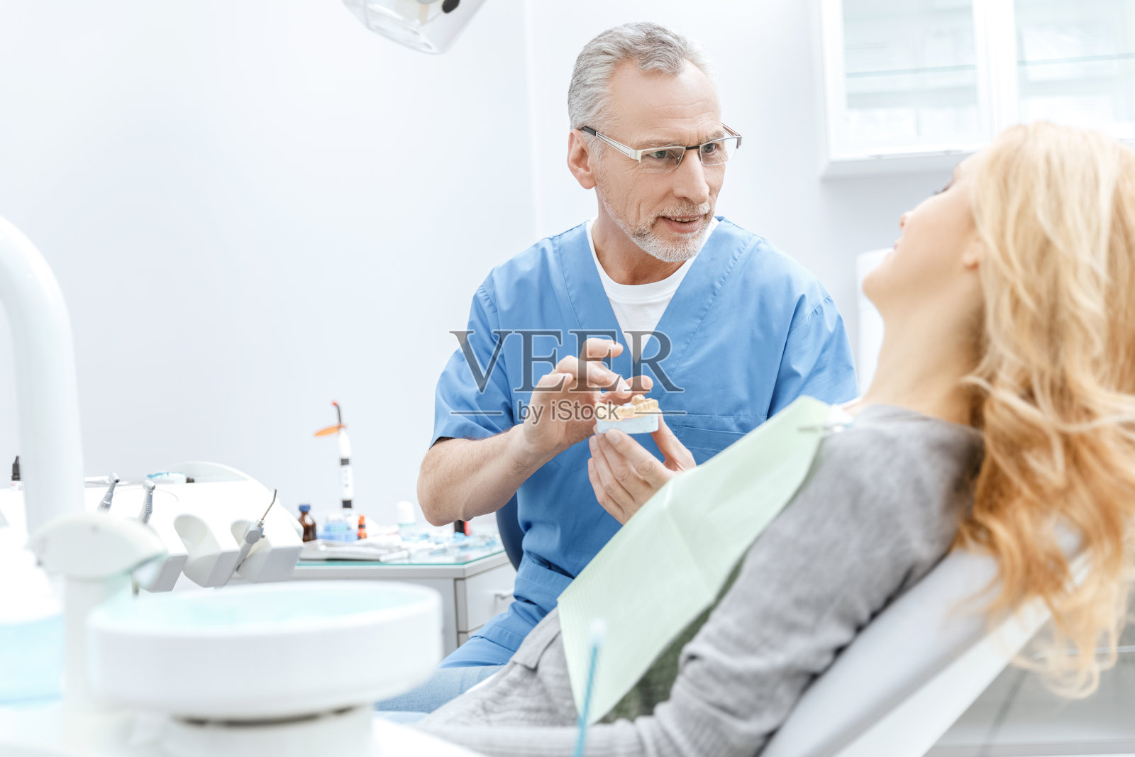 牙科医生在牙科诊所向病人展示下颌模型照片摄影图片