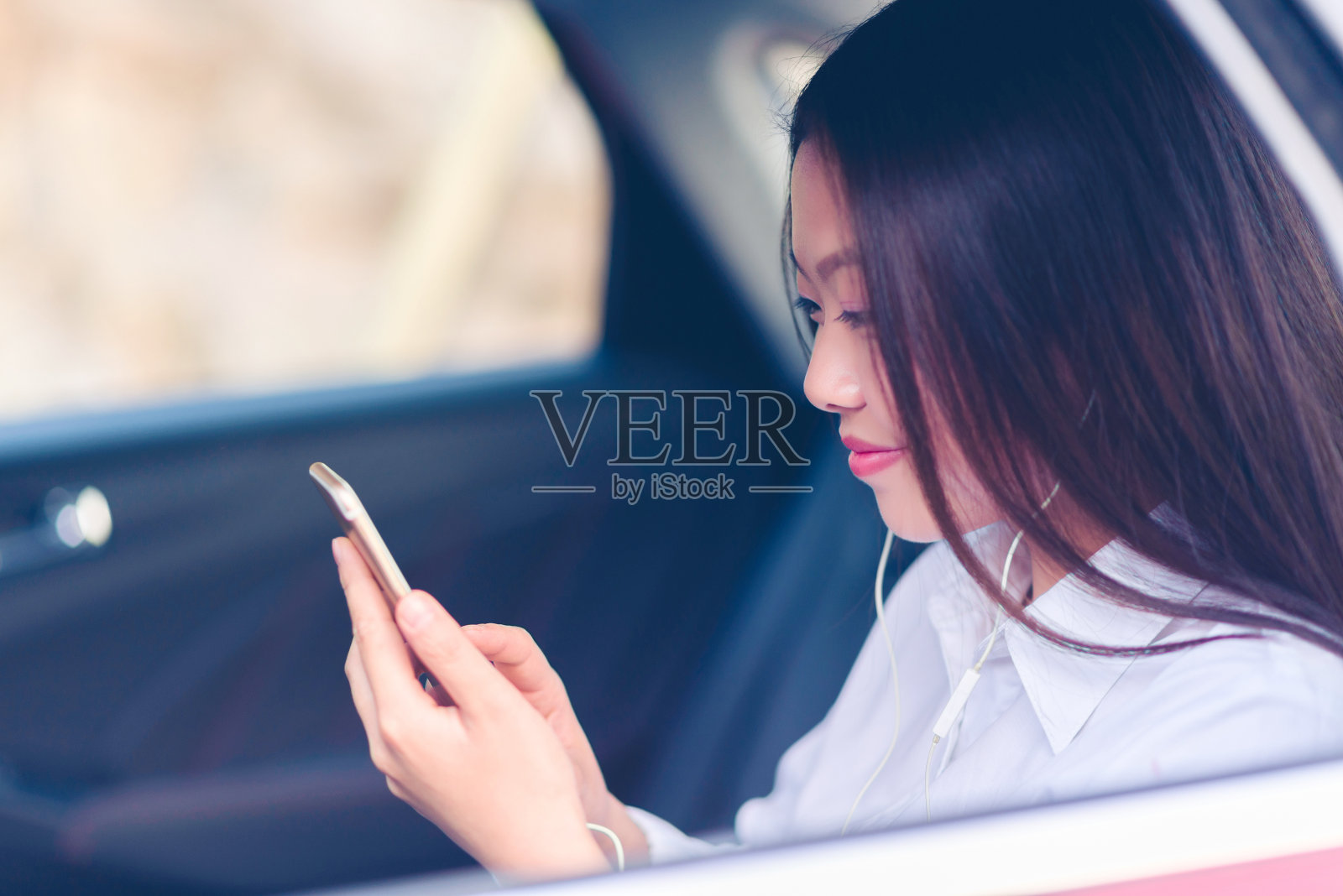 中国年轻女子在车里使用智能手机。照片摄影图片