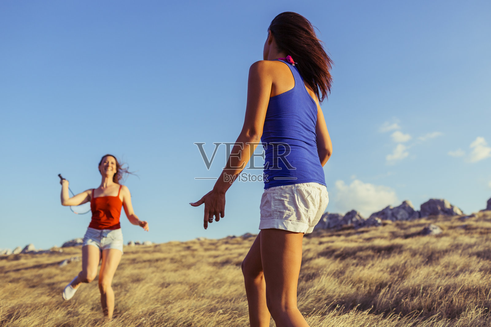 年轻女子在山顶上打羽毛球照片摄影图片