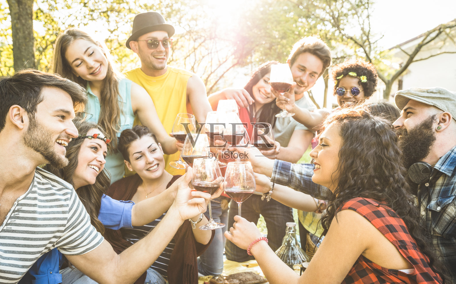 一群朋友举杯红酒在户外烧烤野餐欢呼-年轻人一起享受夏天的时间在午餐花园派对-青年友谊的概念-重点在碰杯照片摄影图片