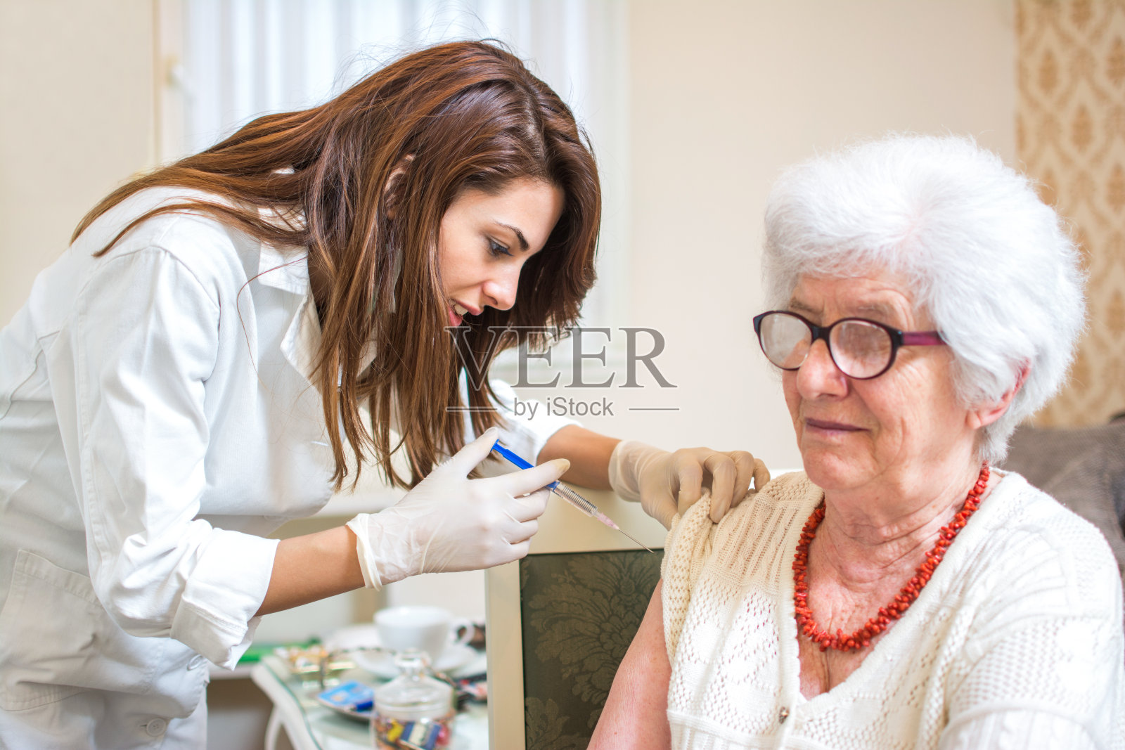 家庭保健护士给老年妇女打针。照片摄影图片