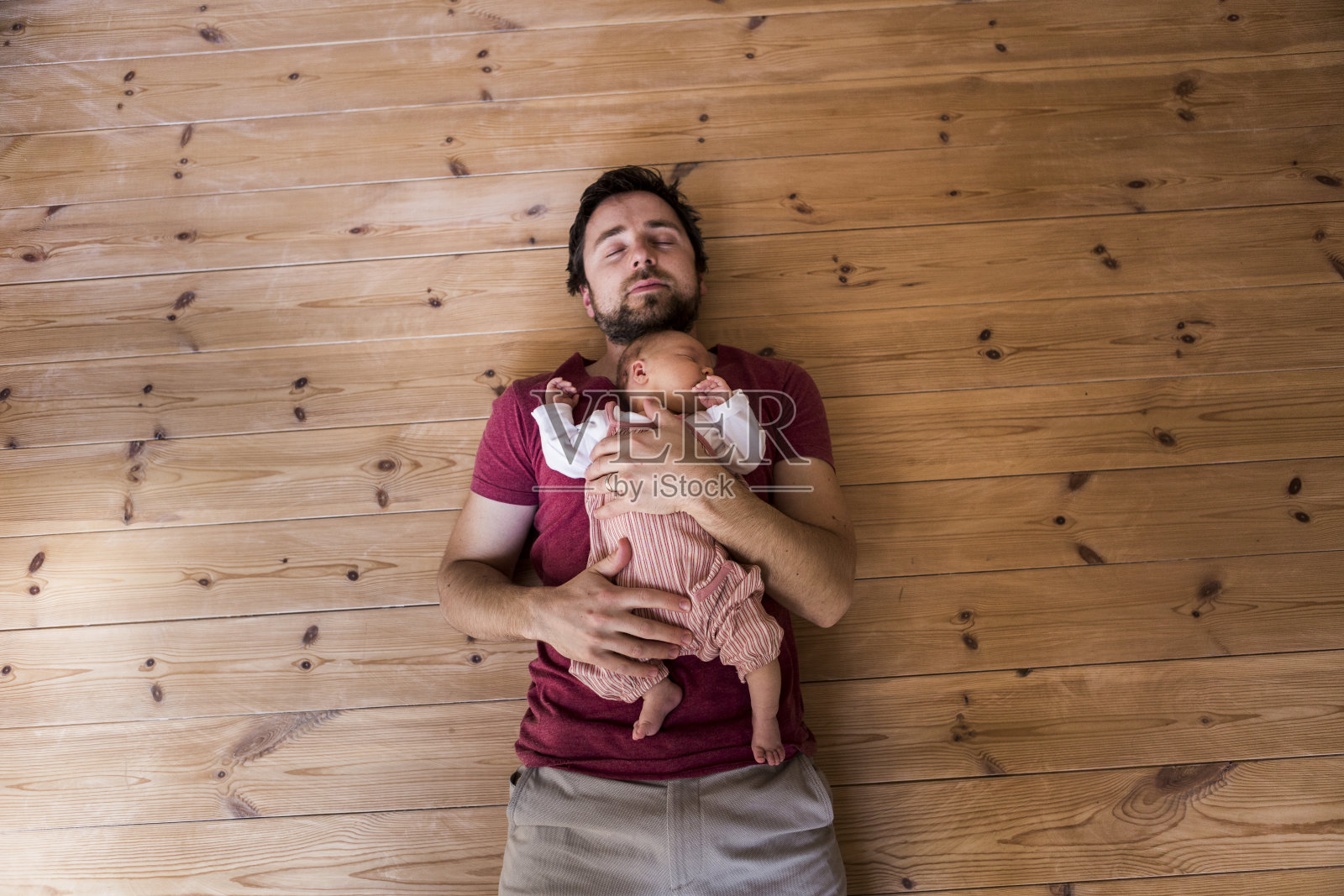 父亲抱着刚出生的女婴，木背景。照片摄影图片
