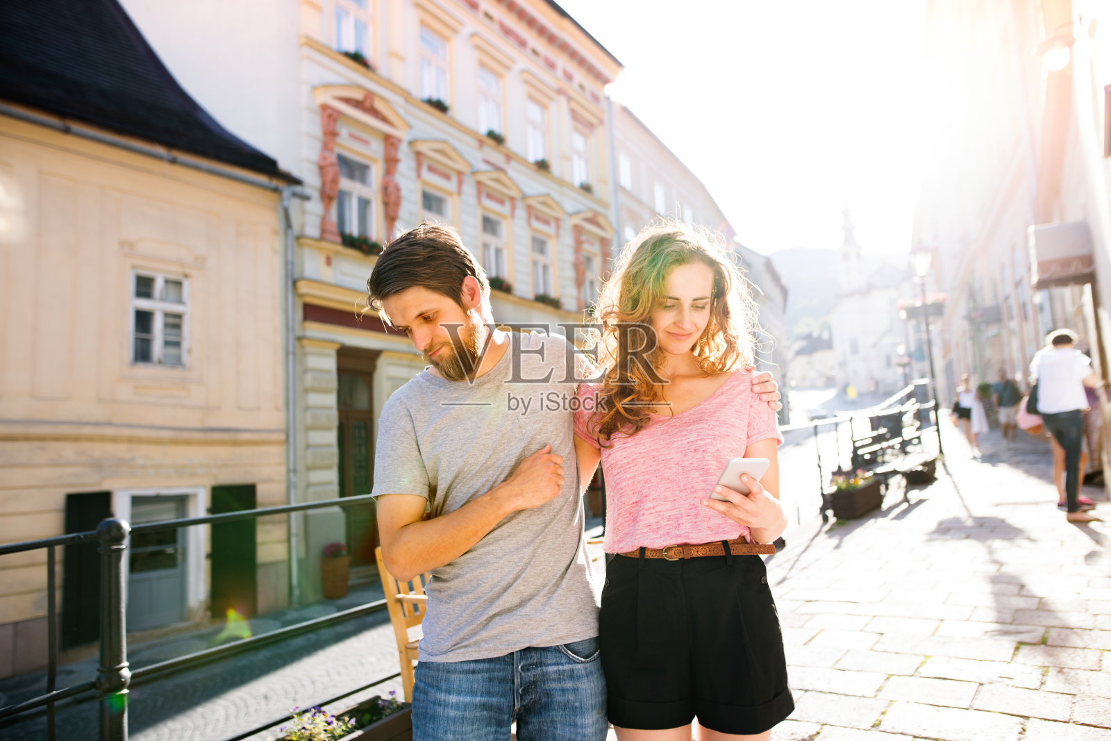 一对年轻夫妇在街上拿着智能手机。照片摄影图片
