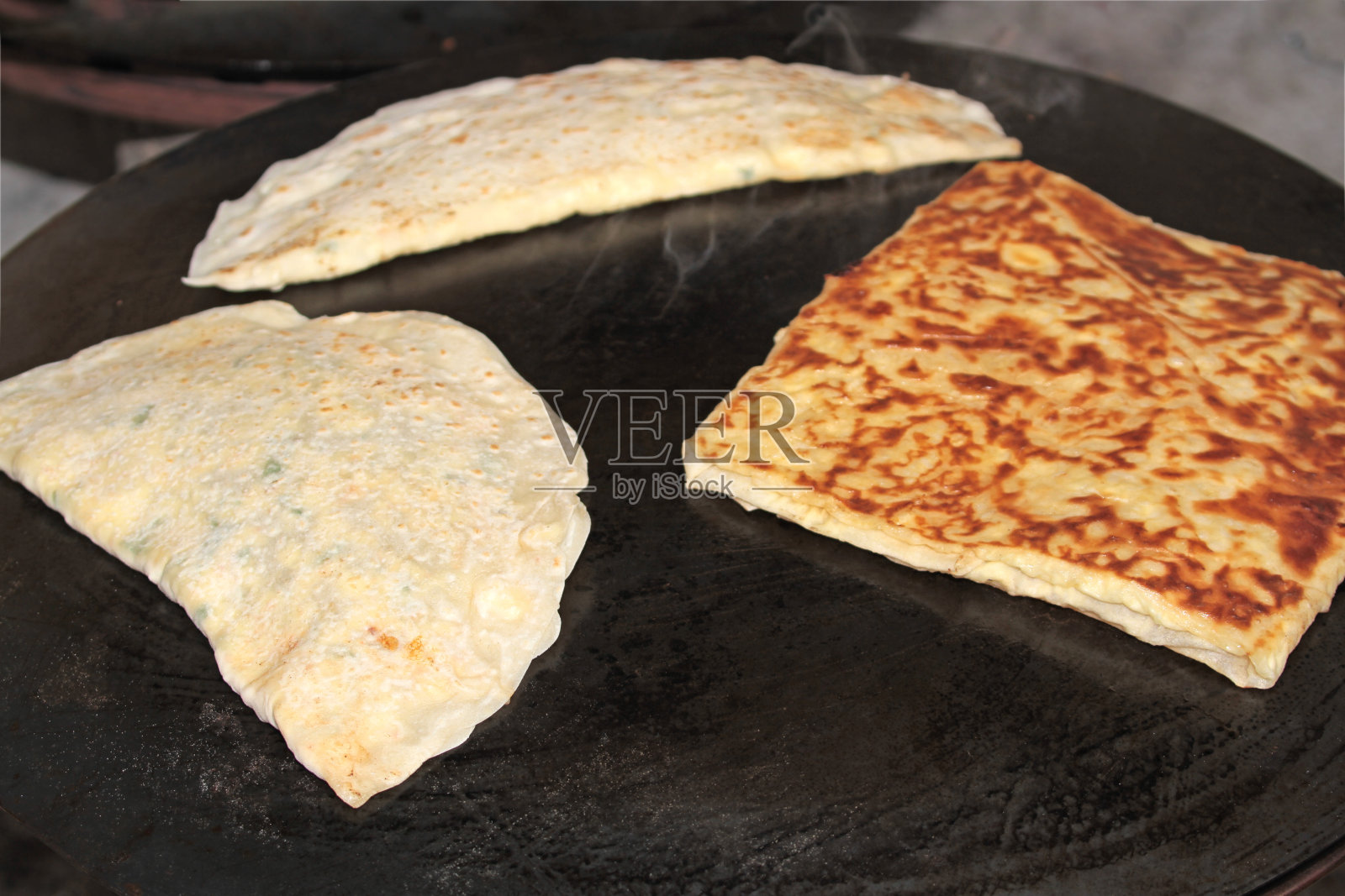 土耳其Gozleme。Gozleme是一道传统的土耳其菜，特色是用扁面包填充各种美味的馅料。在铁皮上烤。照片摄影图片