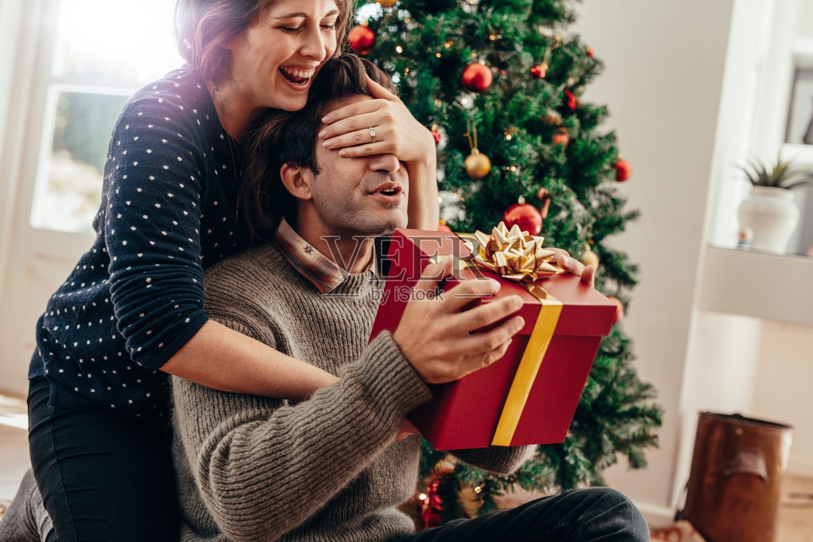 年轻夫妇有乐趣庆祝圣诞节与礼物。照片摄影图片