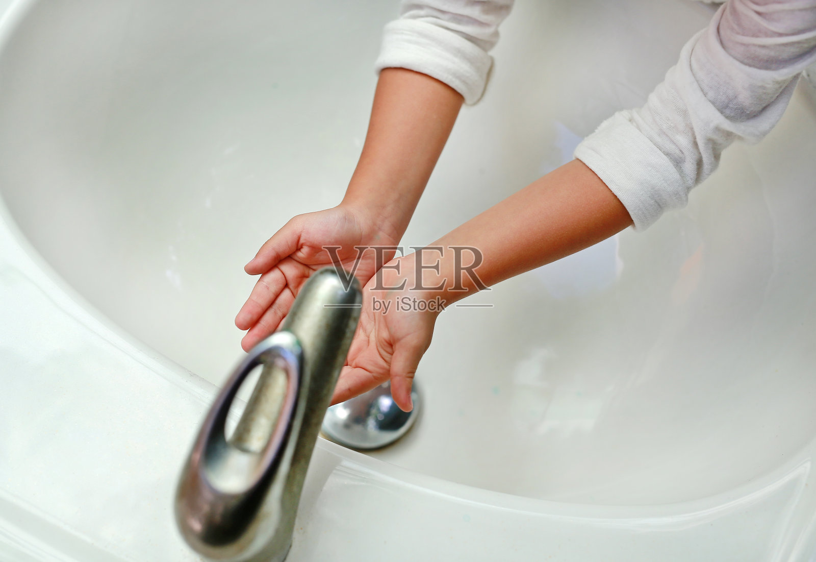 一个孩子的手在水龙头下的水。洗手。照片摄影图片