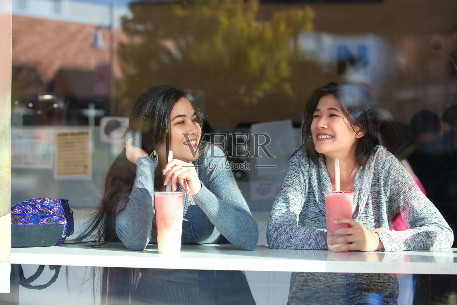 两个十几岁的女孩在户外咖啡馆一起喝珍珠茶照片摄影图片