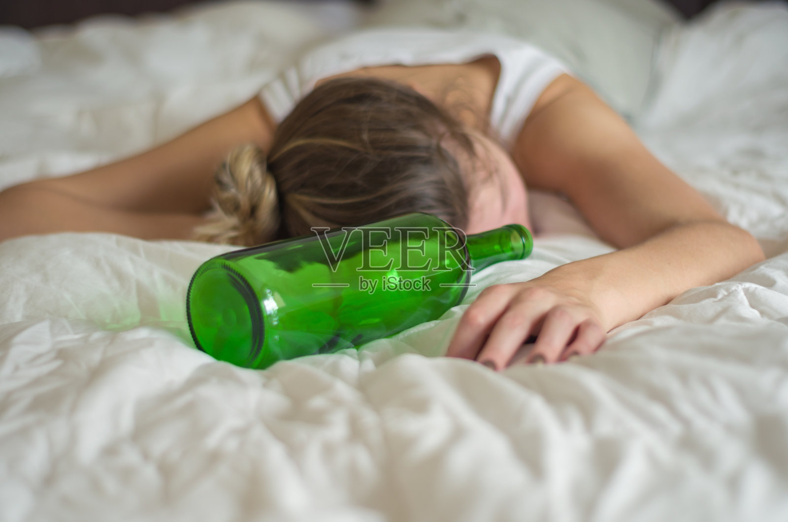 金发女人喝酒后晕倒在床上照片摄影图片