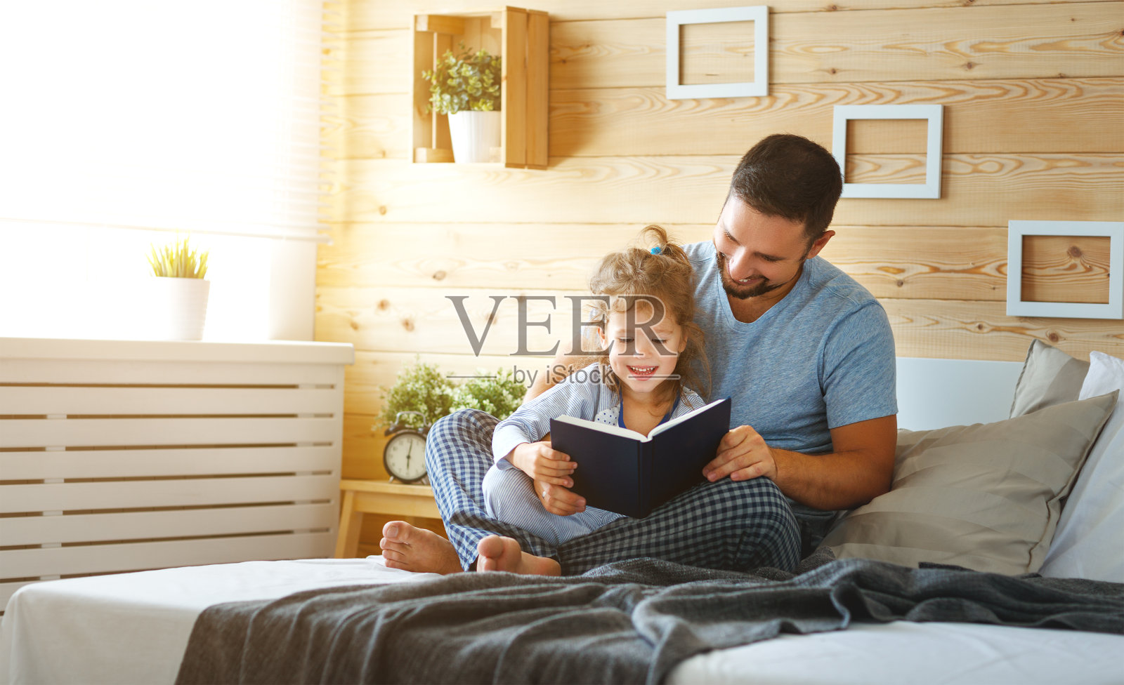 幸福的家庭，爸爸和女儿在床上看书照片摄影图片