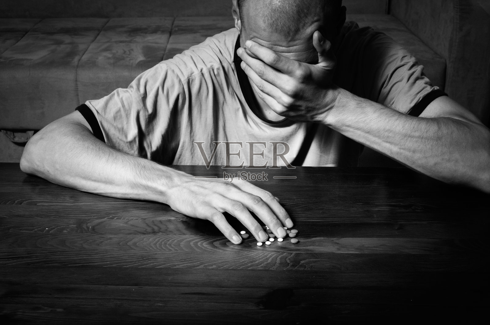 患有自杀抑郁症的抑郁症患者想要通过服用强烈的药物和药丸自杀，而他坐在他黑暗的房间的地板上黑白的图像照片摄影图片