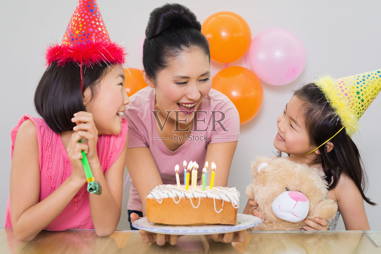在生日聚会上，女孩们看着妈妈拿着蛋糕照片摄影图片