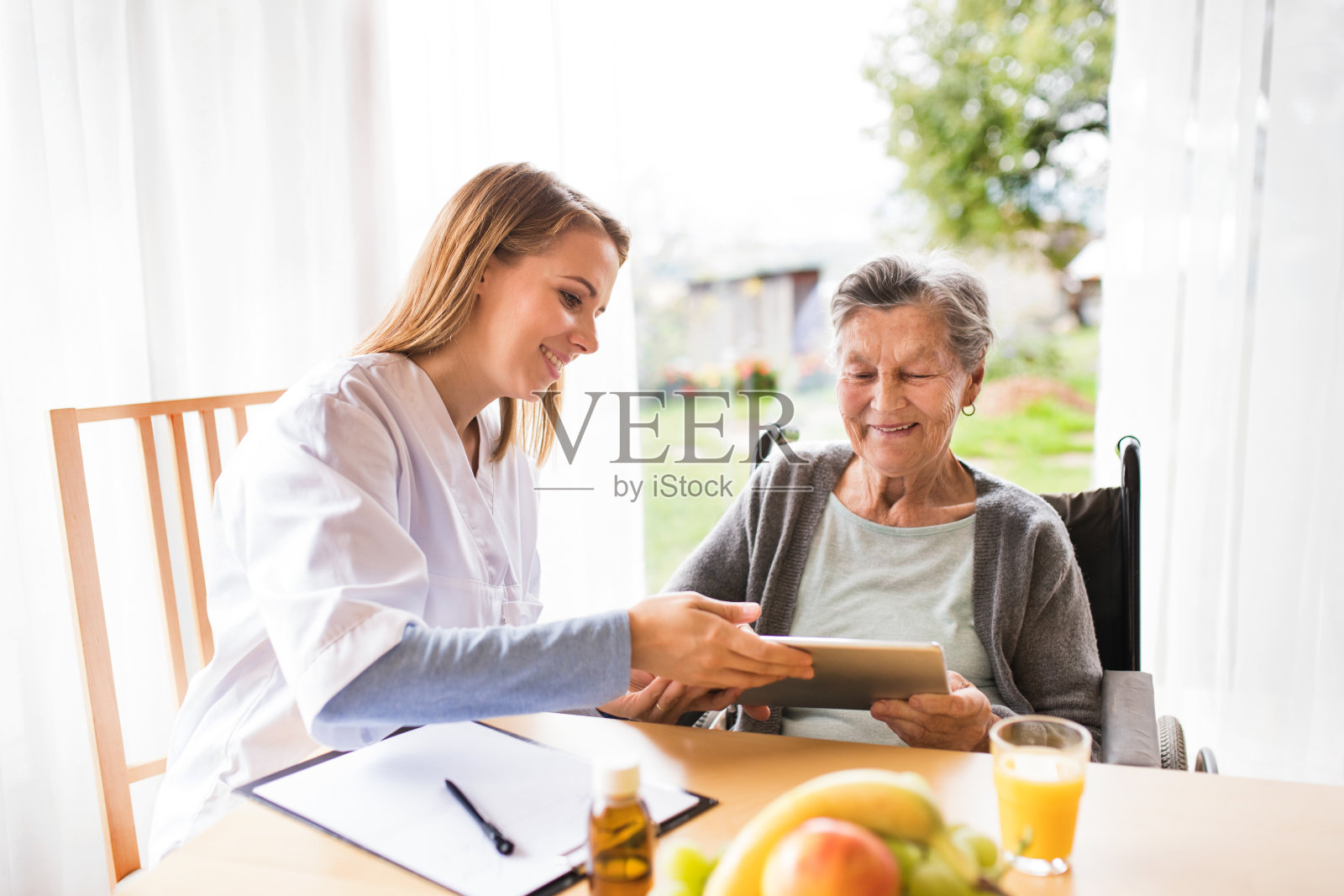 健康访视员和一位服用药片的老年妇女。照片摄影图片