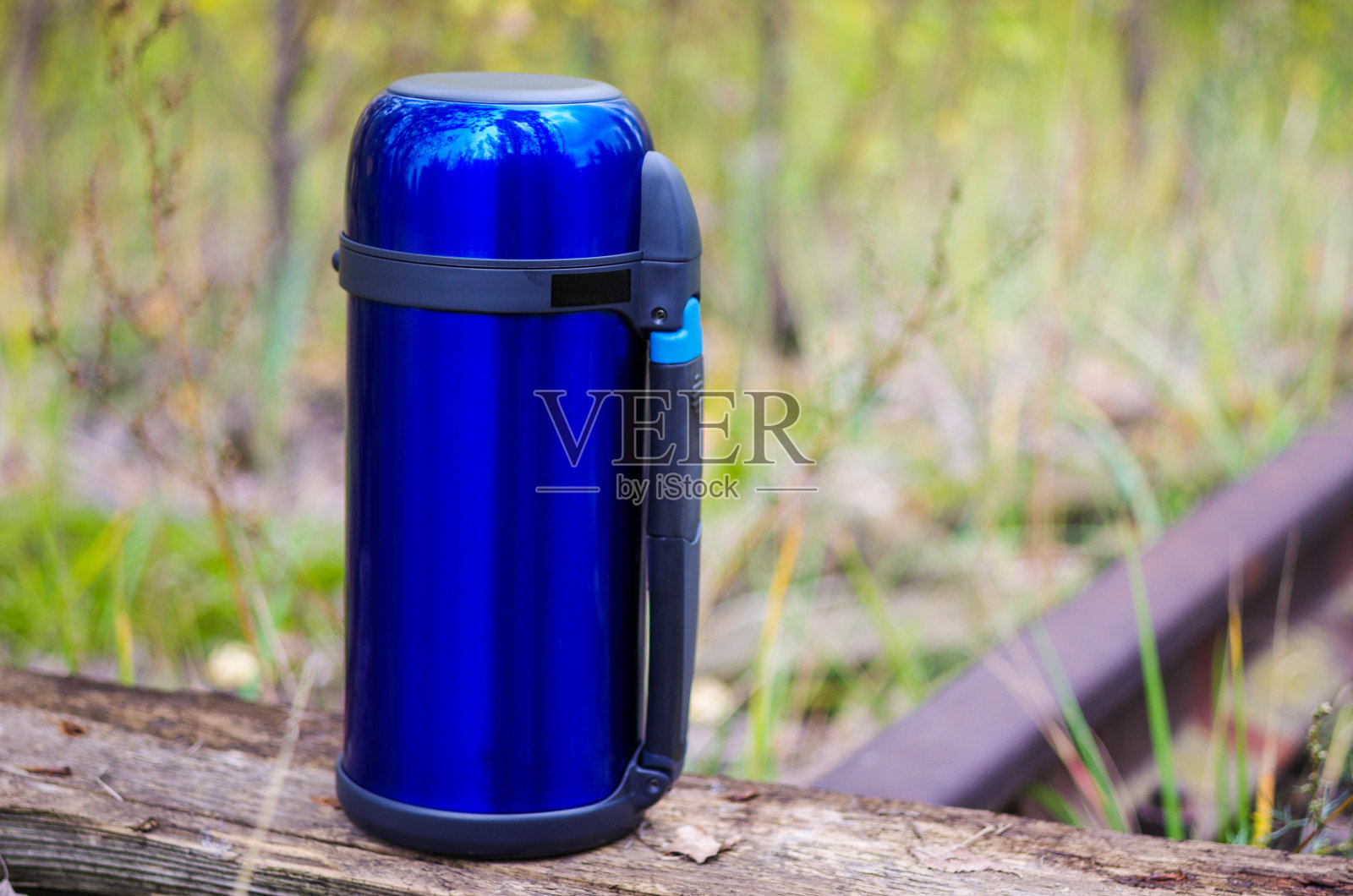 保存热饮的蓝色保温瓶。左边是热水瓶。秋天。照片摄影图片