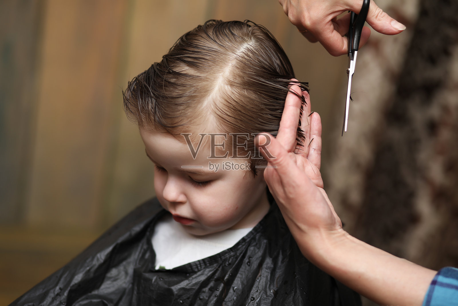 一个小男孩被美发师欢快的情绪迷住了照片摄影图片