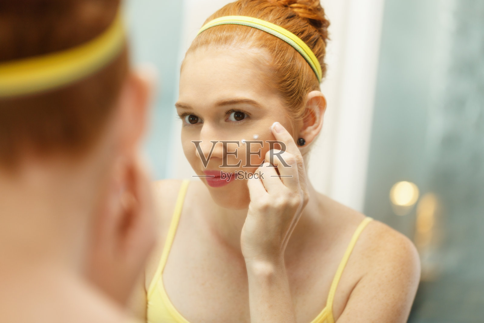 年轻女子在镜子前涂抹抗衰老霜照片摄影图片