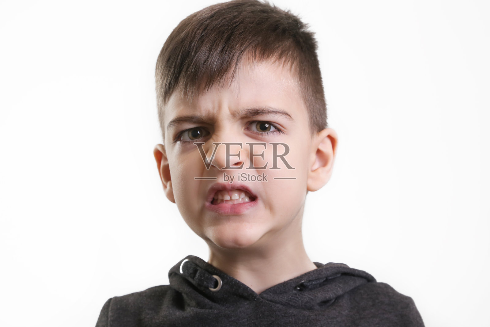 画室里的5岁学龄前男孩的白色背景——愤怒的面部表情照片摄影图片