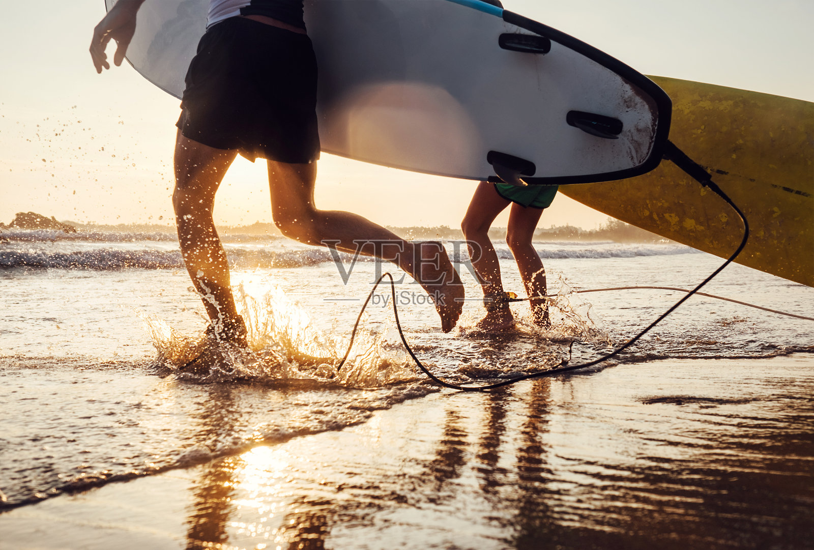 父子冲浪者用长板在海浪中奔跑。近距离飞溅和腿的形象照片摄影图片