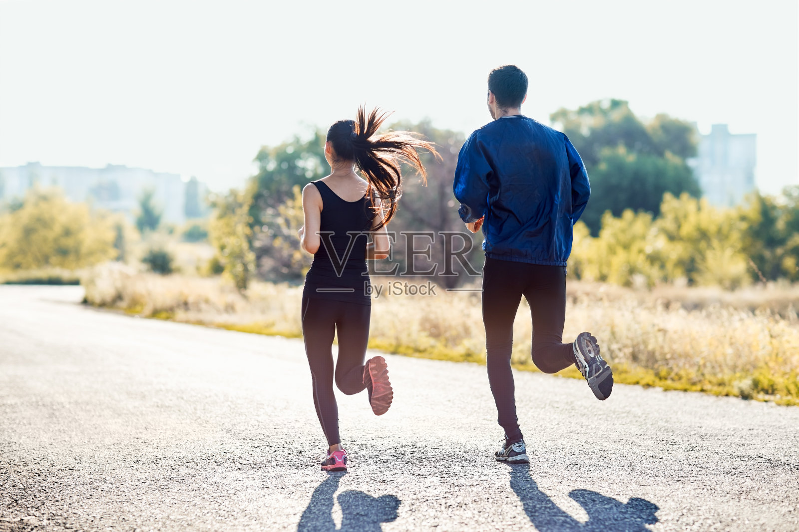 在阳光明媚的日子里，积极运动的女人和男人慢跑照片摄影图片